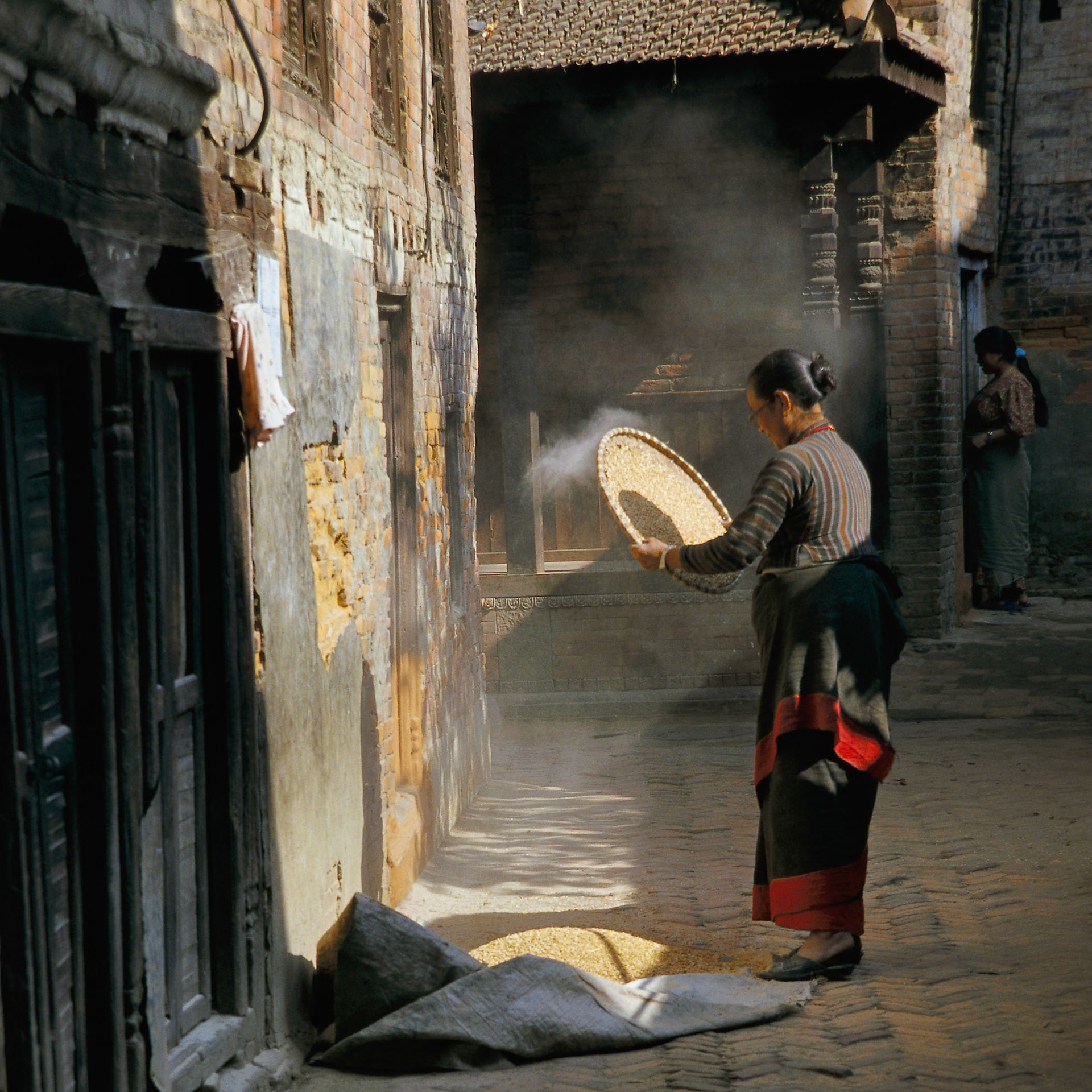 This is one of my favourite photographs. When I came upon this scene the lady was not winnowing but I saw  the potential and waited quietly for several minutes before I took this photograph. For my afternoon in Bhaktapur, I decided to use Fuji Astia to get great skin tones.
