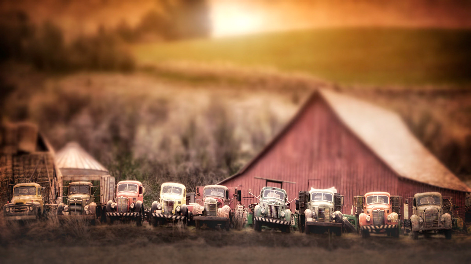Colorful old tow trucks all lined up in front of a red barn in Eastern Washington.