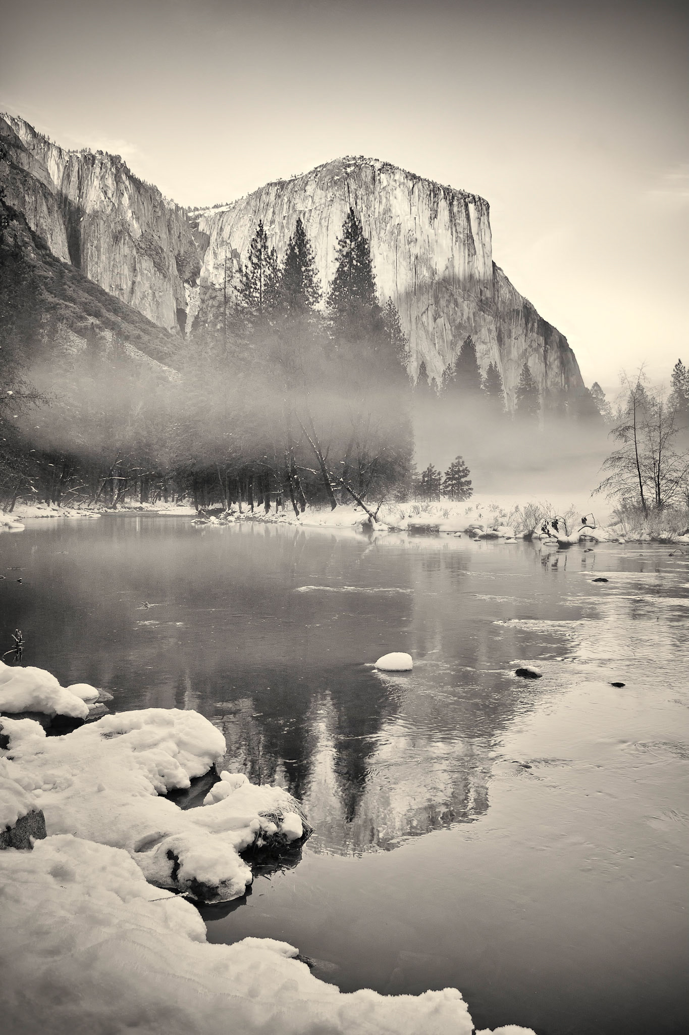 Black and White Image of El Capitan reflected in the Merced River in winter with morning fog and snow in the Yosemite Valley.  Yosemite National Park, CA.