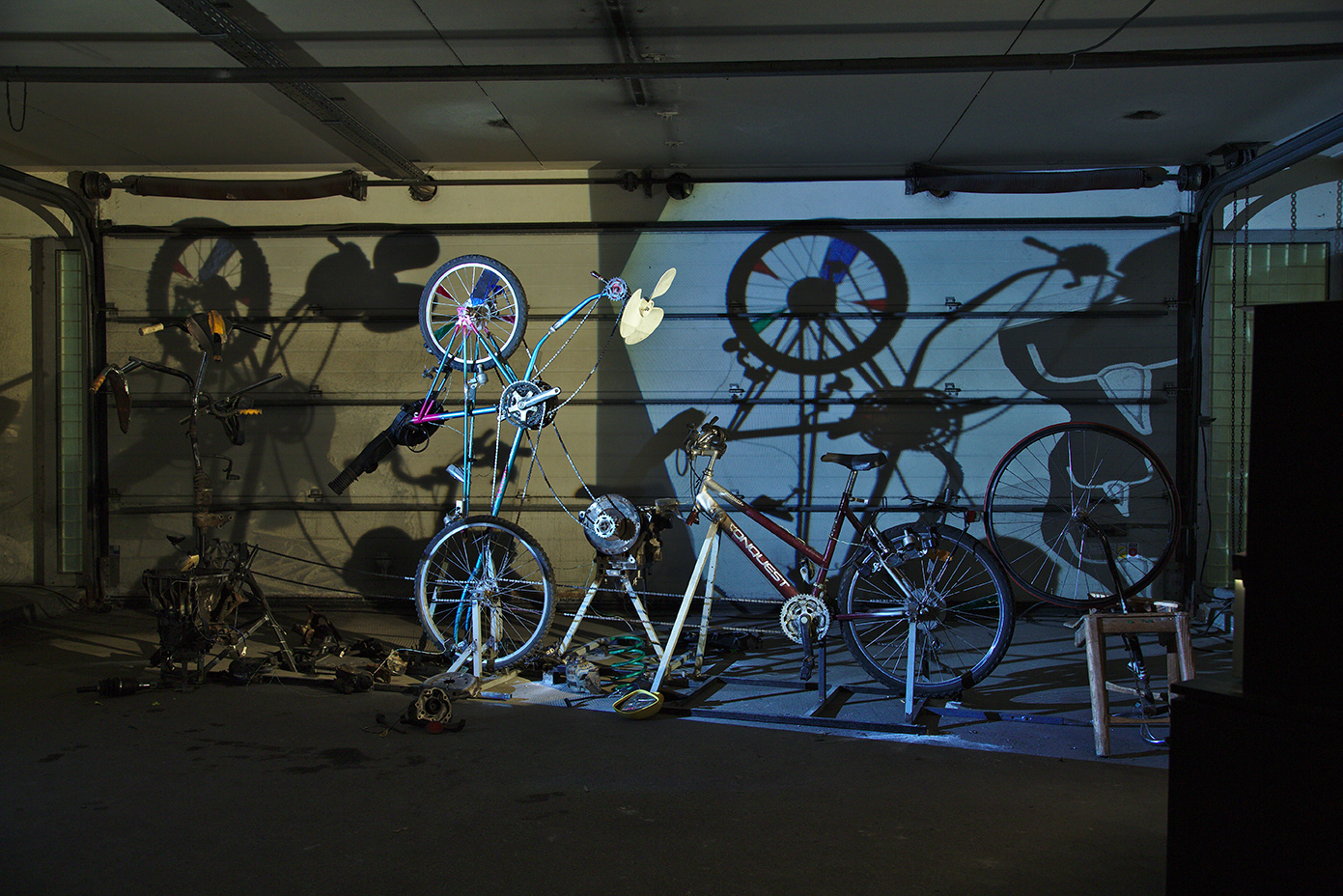 Auto-Mobile (Michael Oskar Wlaschitz & Sabine Watschka) / 2015 / Rauminstallation mit beweglichen Elementen in der Ausstellung „Between Darkness and Light“ der Künstlerischen Praxis am Institut für Kunst und Bildung der Kunstuniversität Linz, ehemalige Tankstelle, OK-Centrum Linz, 2015-2016 / pedalbetriebenes Mobile aus Fahrrad- und Auto-Komponenten, Schattenspiel / 2,00 x 5,00 x 3,00 m / Foto: Christa Amadea