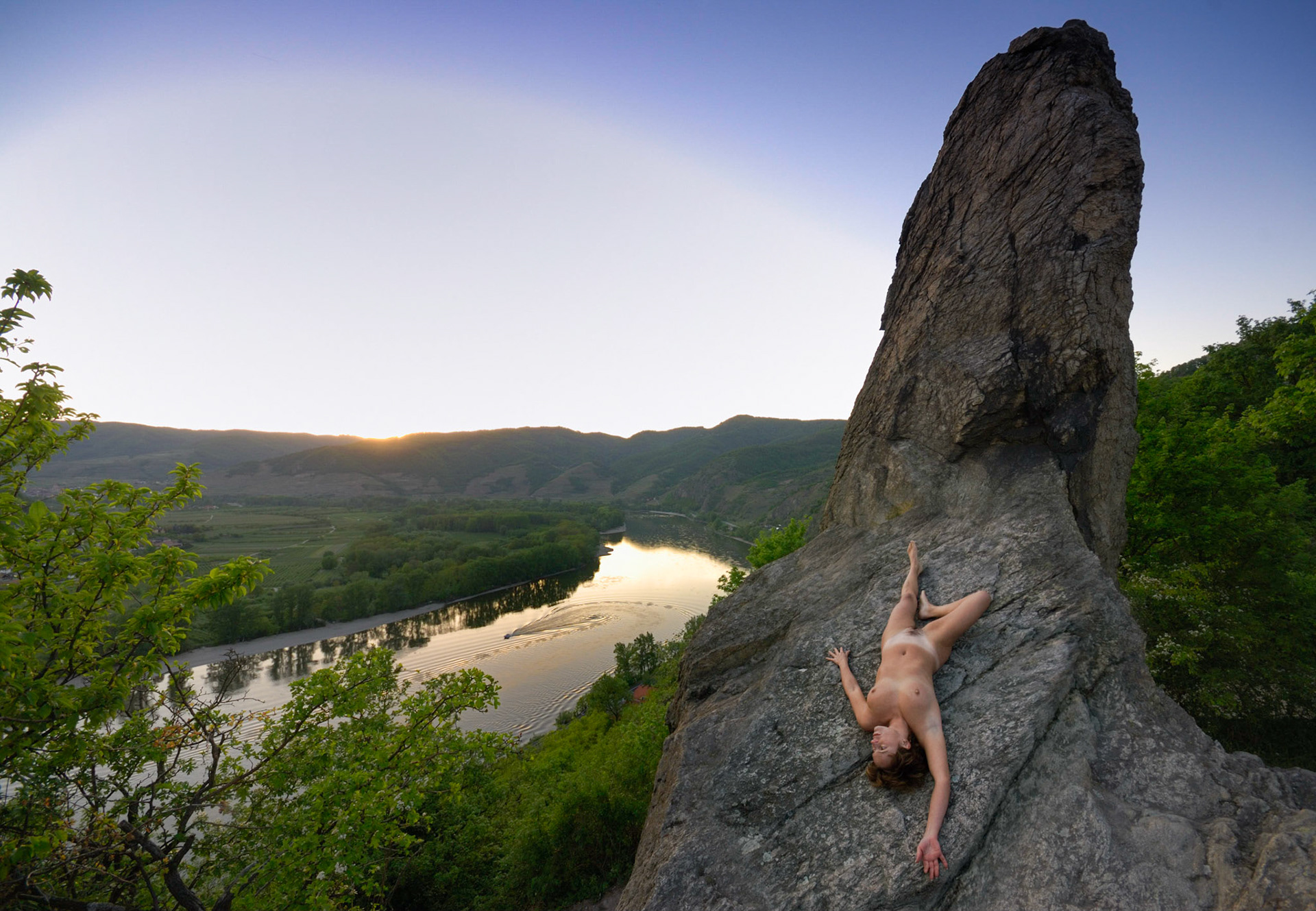after sunset lies a nude woman on a rock in the danube valley