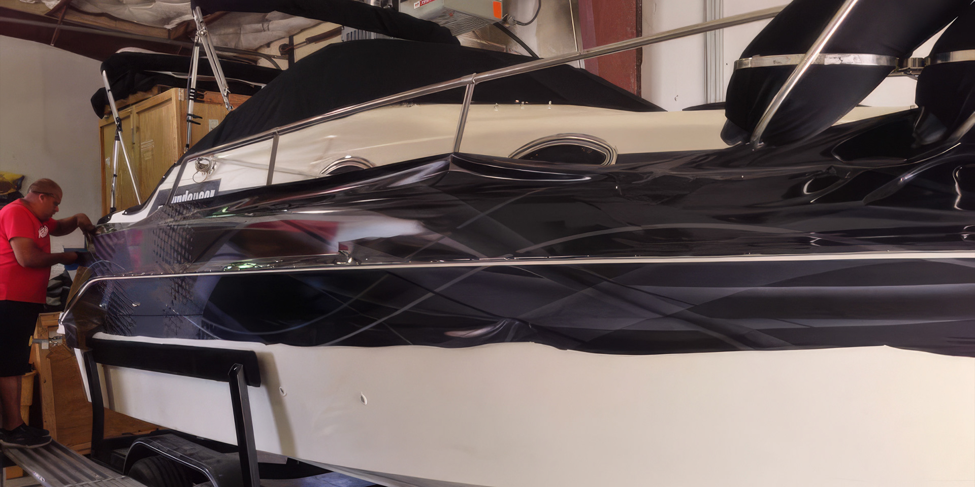 Photo of a vinyl wrap on a boat being installed by an installer.