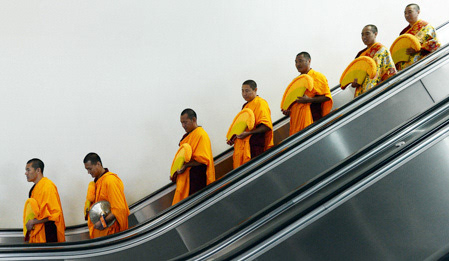 Tibetan Buddhist monks descend an escalator at the Morial Convention Center. The monks chanted Tuesday, May 14, 2013 in an event to highlight the Dalai Lama's visit to the city this week. The monk will also construct a sand mandala, or picture, in advance of the holy man's visit.