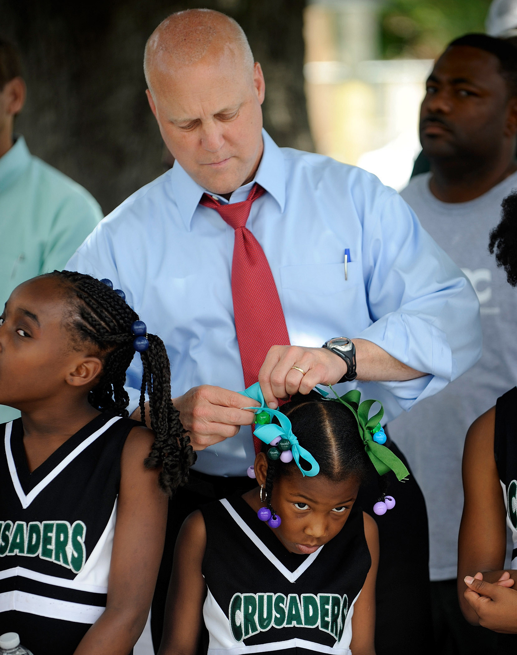 Mayor Mitch Landrieu took time out from a playground ribbon cutting to retie one of cheerleader Kerrau Hymes hair ribbons which came untied while she did a cheer routine.