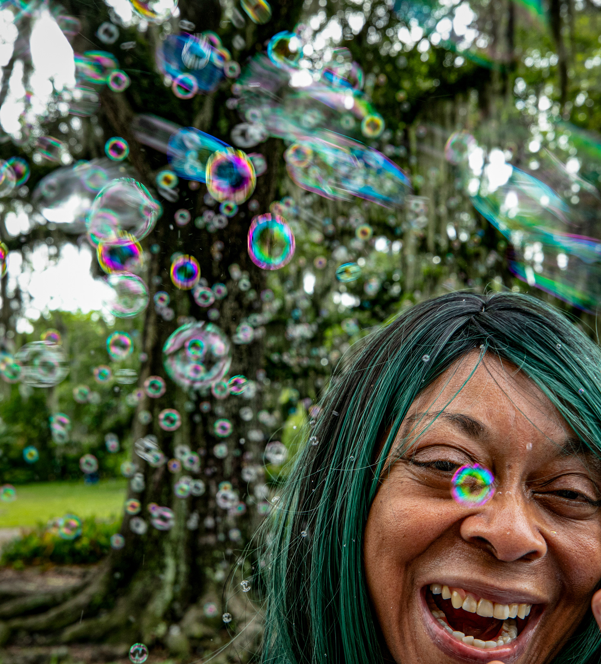 Bubbles fly around Caroline Brock in City Park in New Orleans Sunday, June 2, 2024. From her perch under her bubble machine, Brock shares information on community services like tutoring. 