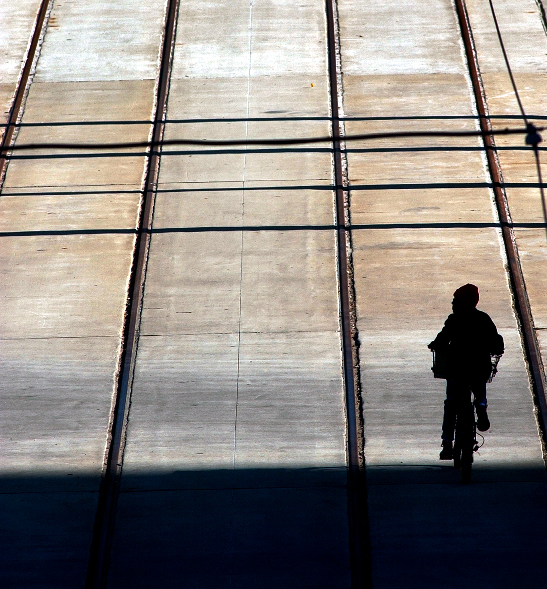 A man pedals his bike down Canal street as seen from the Interstate 10 overpass. The late afternoon sun throws much of the street in shadow.