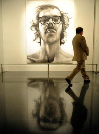 Lee Horvitz walks past the piece "Big Self-Portrait" by artist Chuck Close at a press preview for the new exhibit "Lifelike" Friday at the New Orleans Museum of Art.