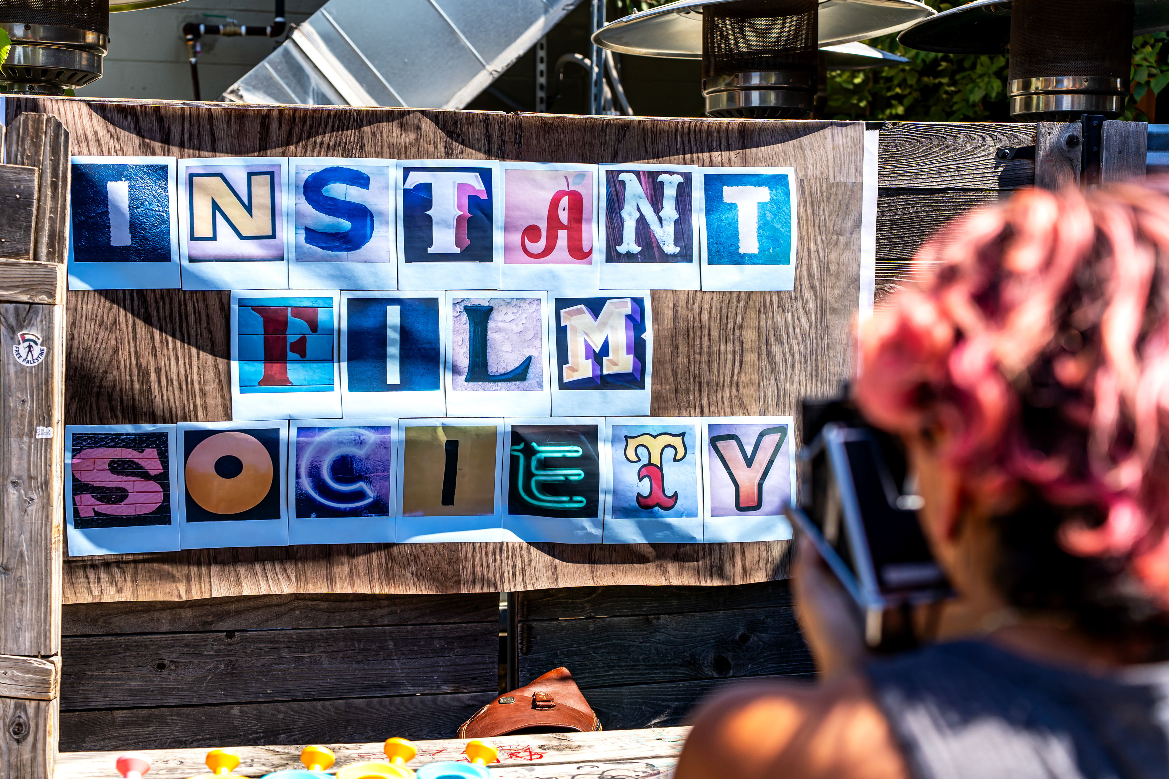 Attendee Ezra Lou takes a Polaroid of the Instant Film Society poster hung at Rubber Globes during Polacon in Denton, TX on Sept. 27, 2025. The Instant Film Society is the organization that hosts Polacon.