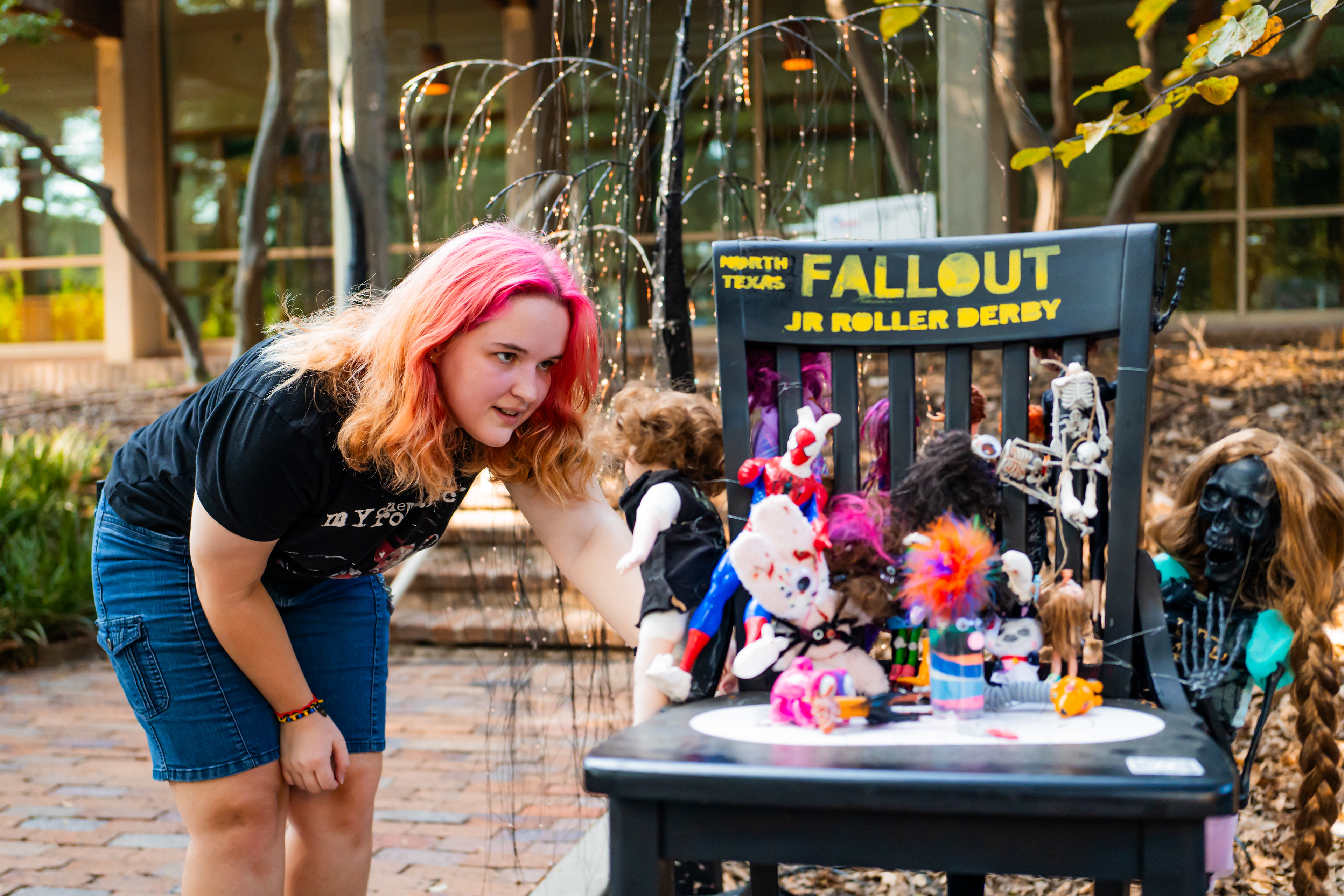 Robin and Fallout Chair: Robin Easley-O’Neil inspects “Fallout JR Roller Derby” chair at the Scary Chairy Orchard ongoing exhibit near Denton City Hall on Oct. 11, 2024