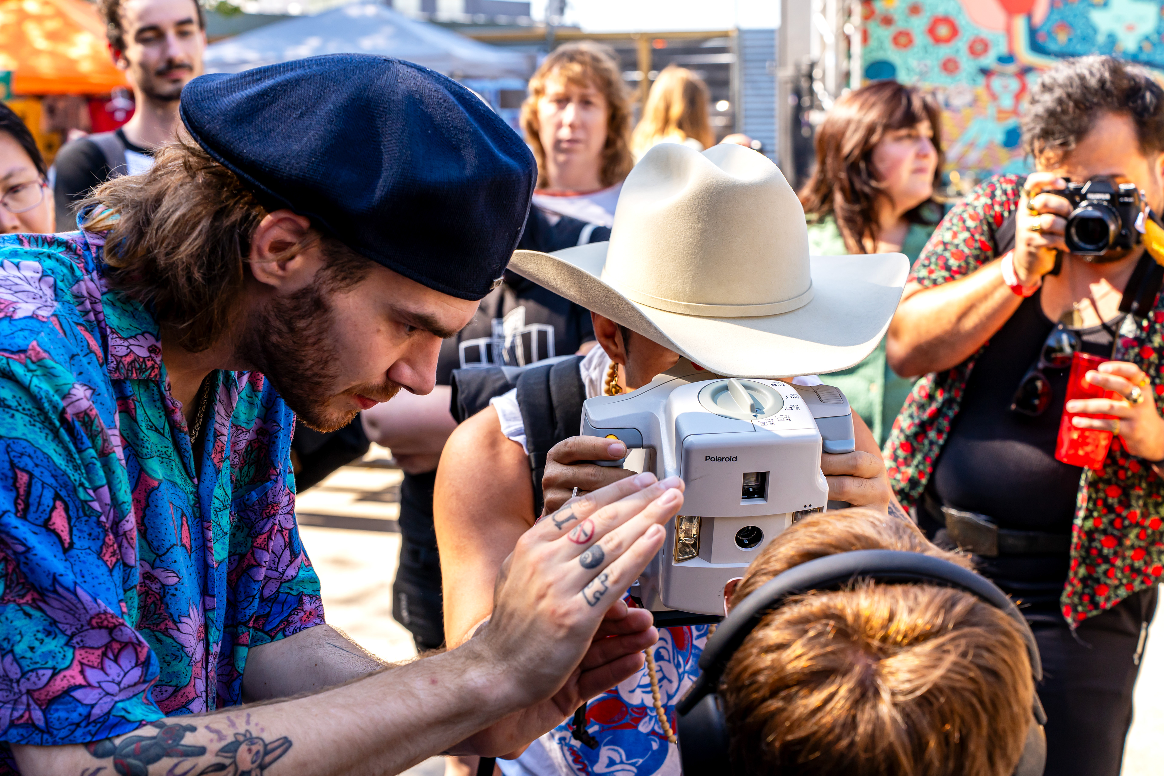 Nick Mass shows an attendee how to take a Polaroid with his Macro 5 SLR Polaroid during Mass' Macro 5 SLR workshop at Rubber Gloves during Polacon in Denton, TX on Sept. 27, 2025.