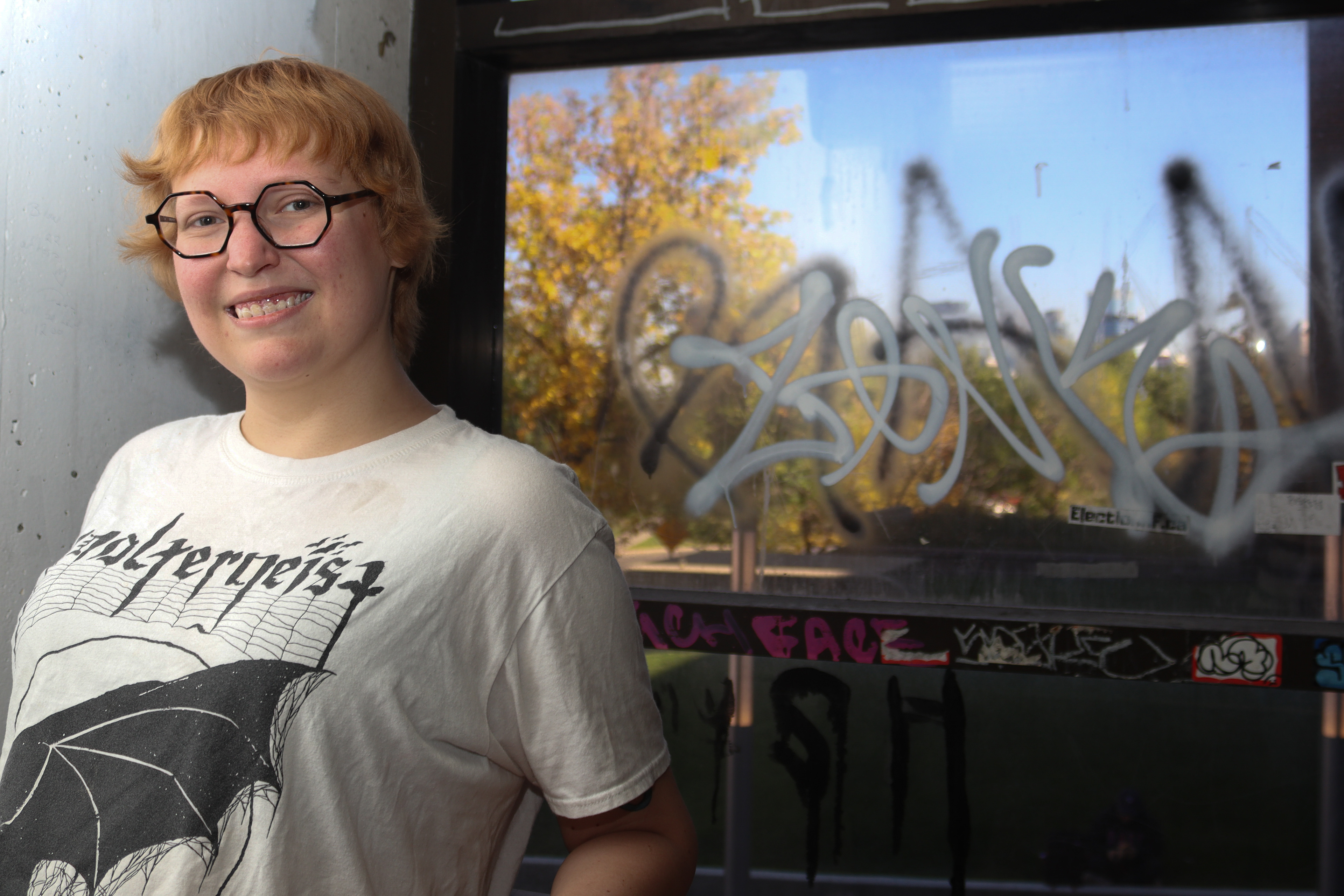 Subject posing in front of graffiti in window