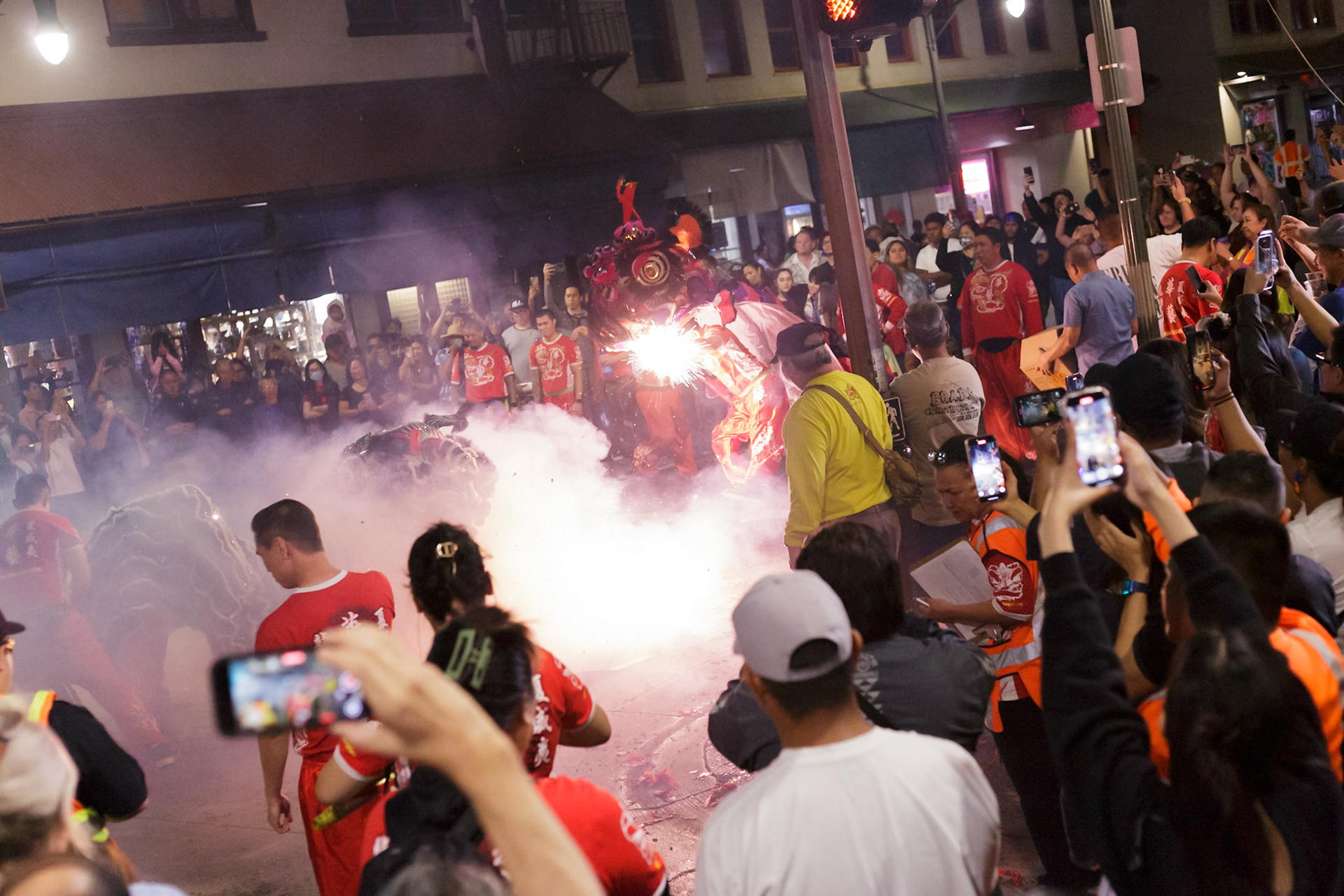 Two lions are dancing around as firecrackers pop near them.