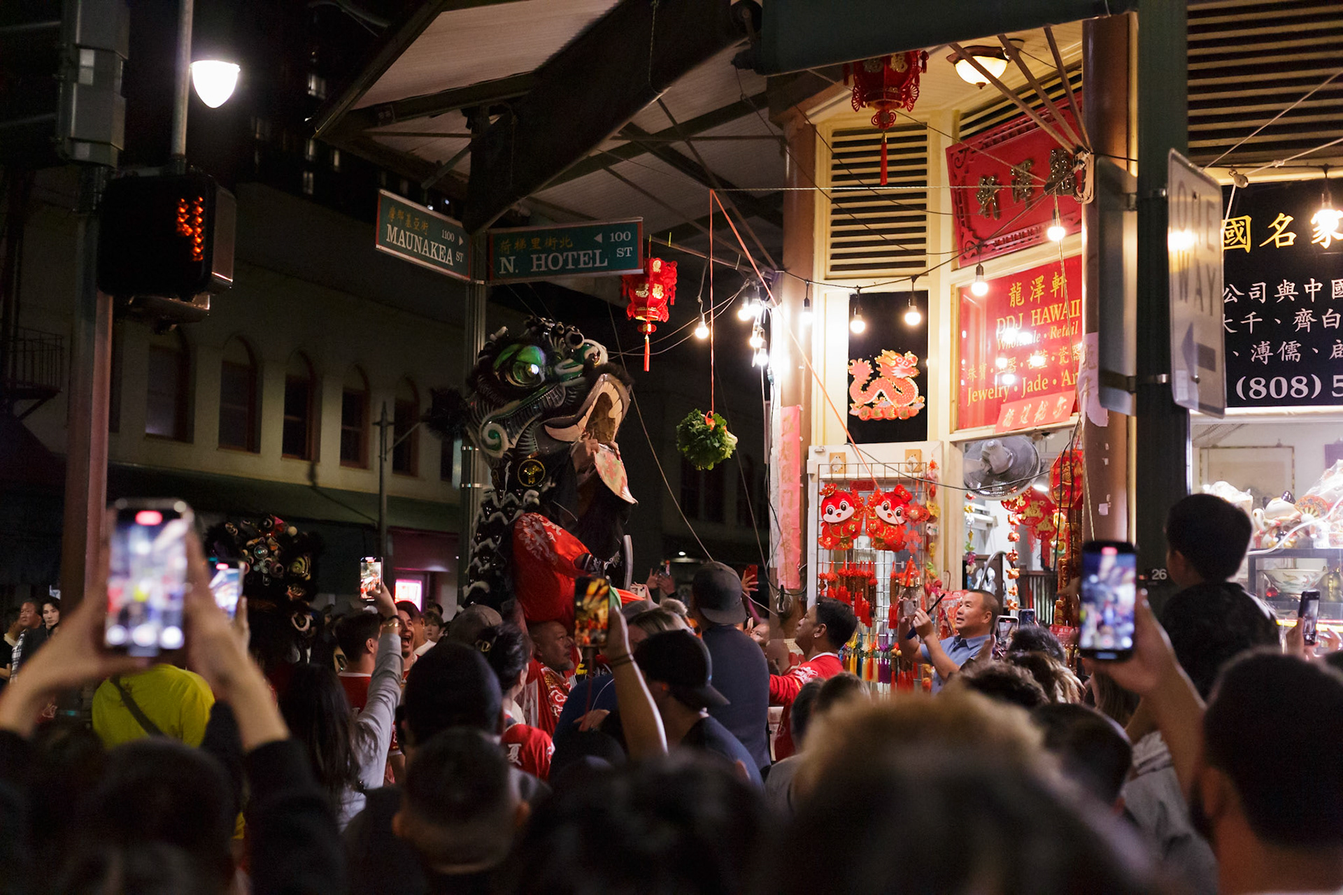 A lion is opening its mouth wide open as it approaches a hanging lettuce in front of a store in Chinatown, Honolulu, Hawaii.
