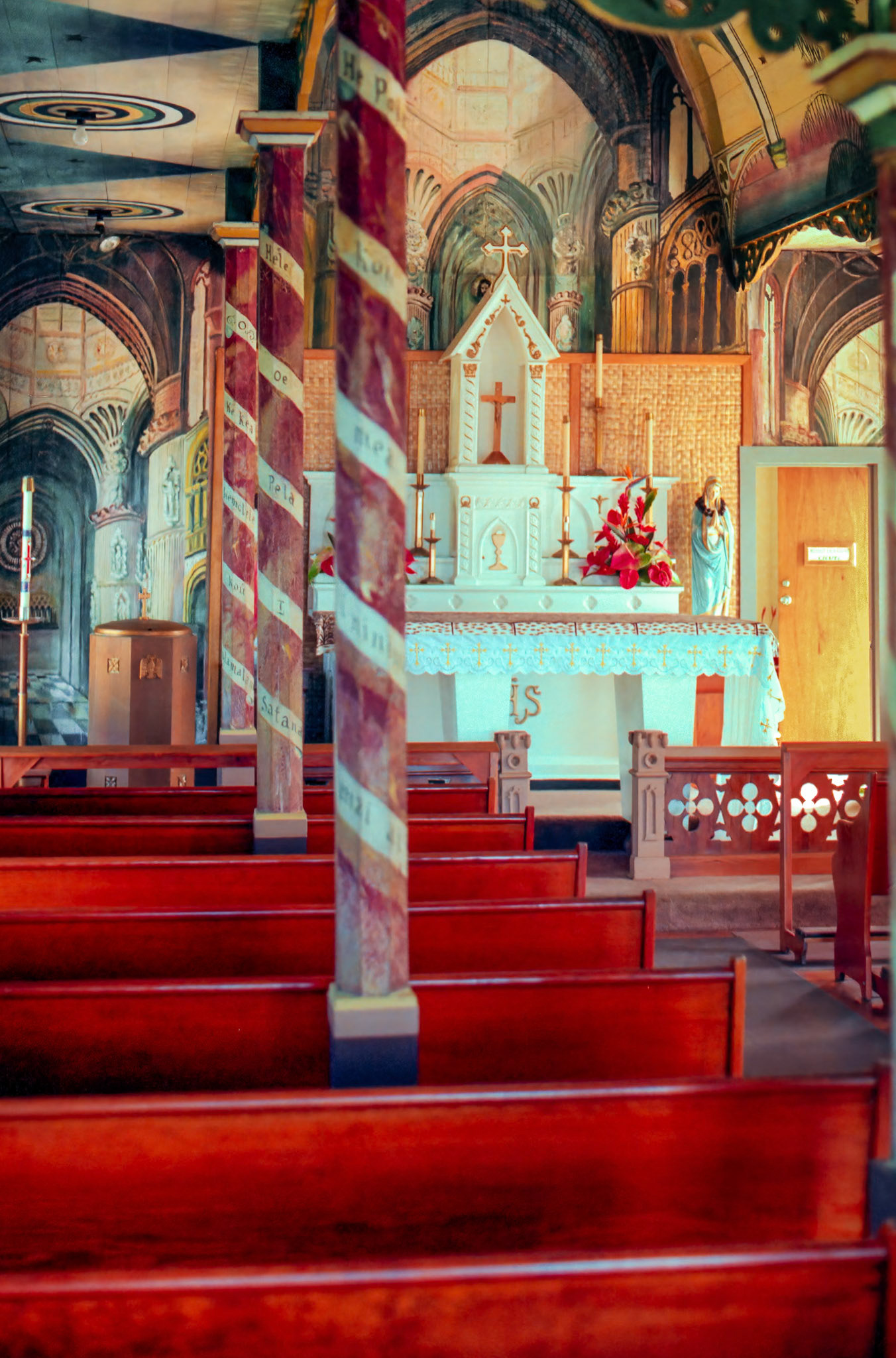 This church, erected at its present location in 1899 on the Island of Hawaii, was painted by a priest from Belgium using house paint on the wood wall behind the altar to depict a gothic cathedral.Image captured on Kodak Royal Gold 100 color negative film. After scanning it with an Epson Perfection V750 PRO using Silverfast software, the ColorPerfect Plugin from CFSystems converted the negative image to a positive image in Photoshop. Post-processing completed in Lightroom Classic.