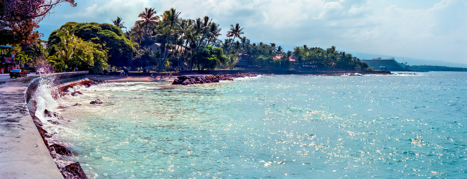 From a section of waterfront that is the traditional starting point of the Hawaii Ironman competition, this section of a breakwater sweeps along the southern flank of Kailua Bay, which is in Kailua-Kona, Hawaii, and reveals another beach protected by a natural breakwater.Two images captured on Kodak Royal Gold 100 color negative film. After scanning Them with an Epson Perfection V750 PRO using Silverfast software, the ColorPerfect Plugin from CFSystems converted the negative images to positive images in Photoshop. Post-processing completed in Lightroom Classic after merging the photos into a panorama in Photoshop.