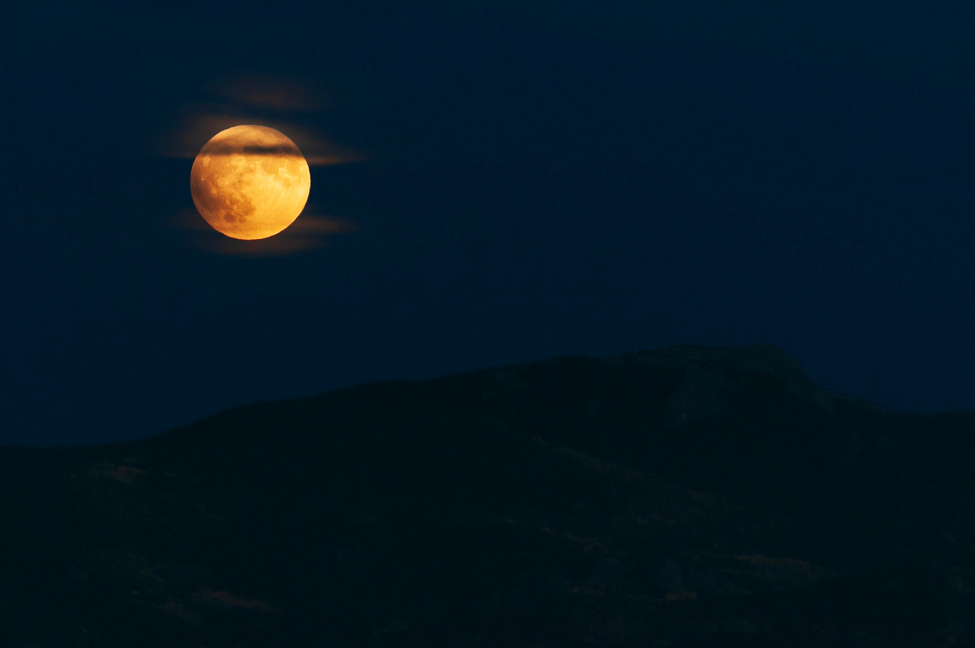 Shortly after rising  above the Tarryall Mountains, which are located at the Eastern edge of the grassland basin known as South Park, some wispy clouds drifted in front of the Super Moon — this moon is also known as the Blood Moon and the Hunter's Moon — a few minutes before entering the umbra and its total eclipse on September 27, 2015.