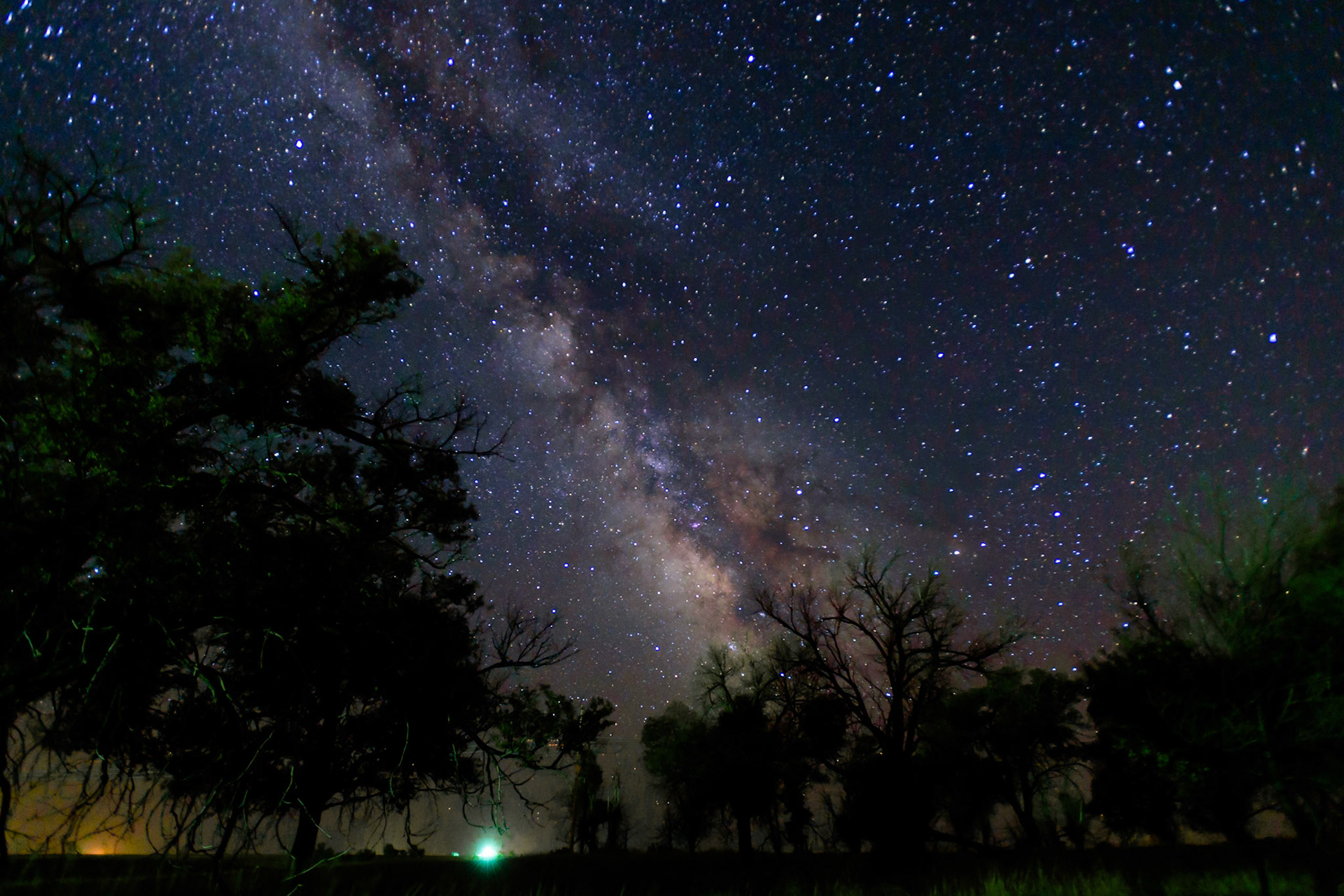 Dark skies for dramatic captures of the Milky Way and its Galactic Center exist on the eastern plains of Colorado, provided one stays away from some of its rural population centers. This photograph was made near Cope, Colorado, which is in a Class 2 (typically truly dark sky) area on the Bortle Scale. Light pollution from Stratton and Bethune, Colorado, which are located more than 40 miles (64 km) from this site, appears in the lower left of the photo. Light from a nearby farm highlights portions of the foreground, and light from another farm is seen as a bright glow on the horizon near the center at the bottom of the photo.