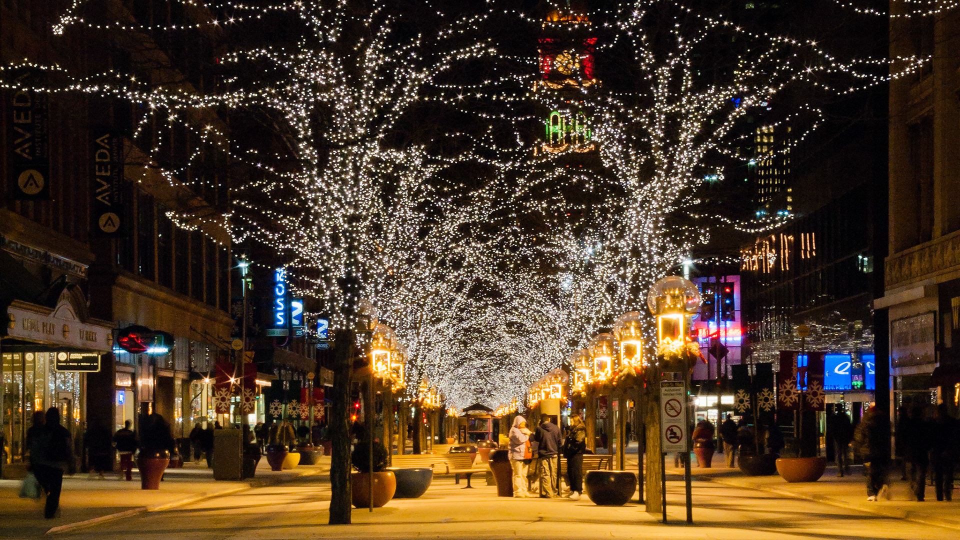 Nighttime shoppers, casual strollers, and friends congregate along the brightly decorated trees along the 16th Street Mall in downtown Denver, Colorado.