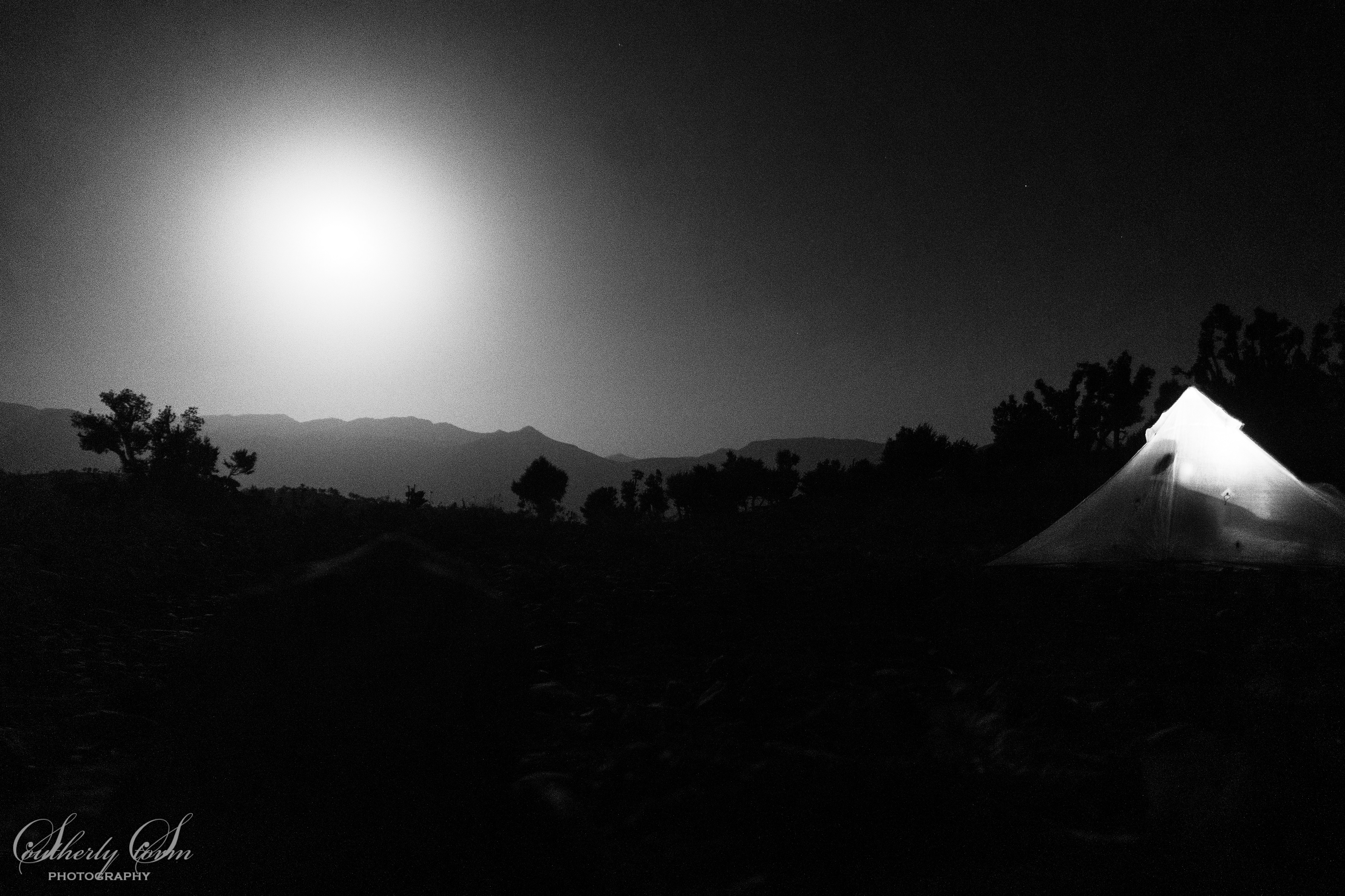 Black and white night image with lit up tent