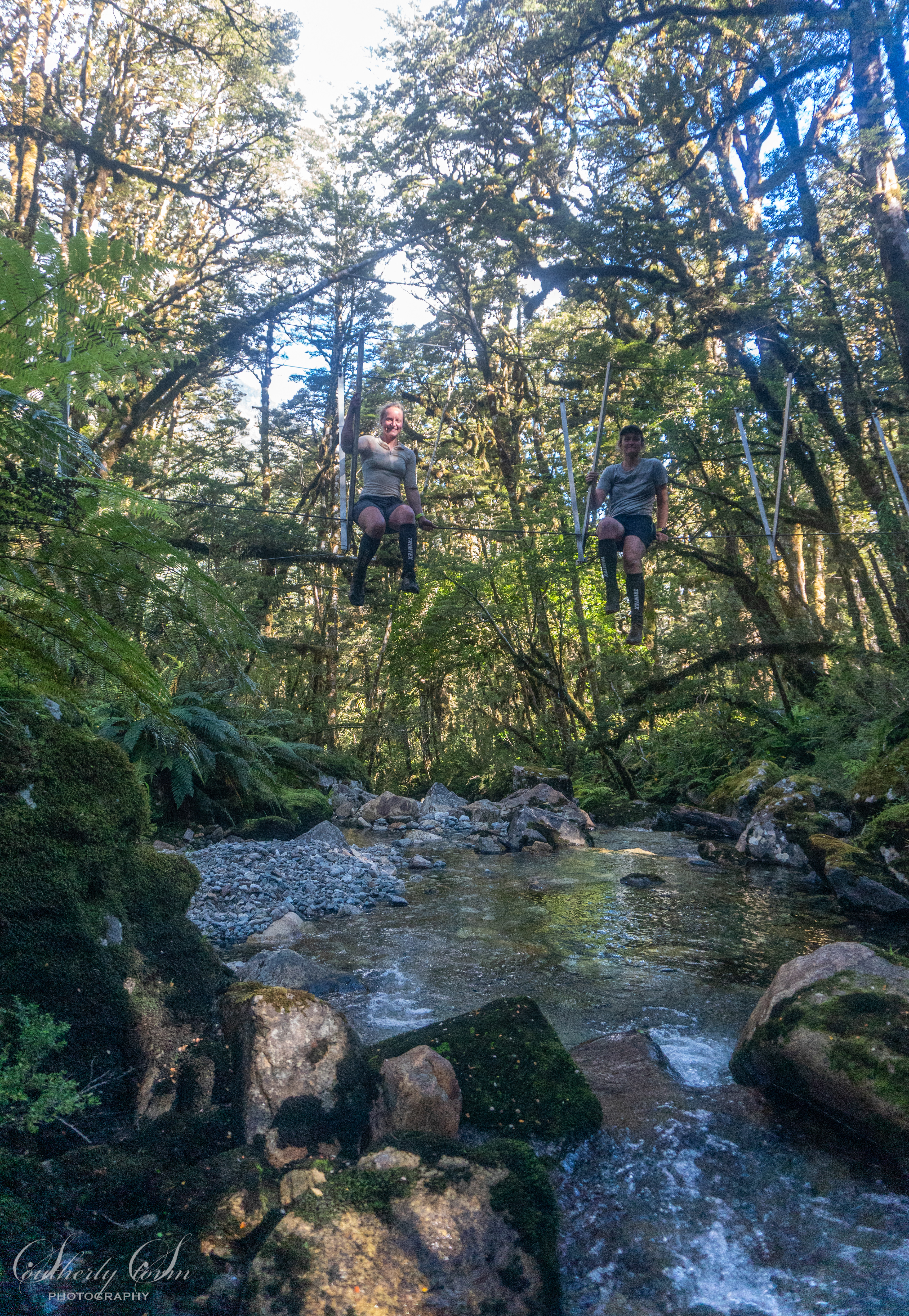 Two trampers sitting on a 3-wire bridge