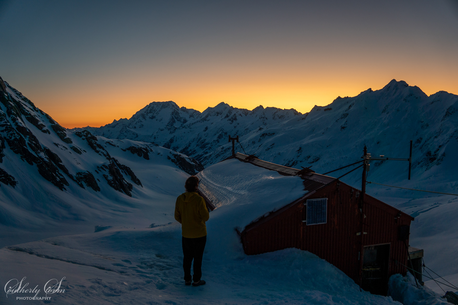 Climber and Tasman Saddle Hut watching sunset on Aoraki Mt Cook