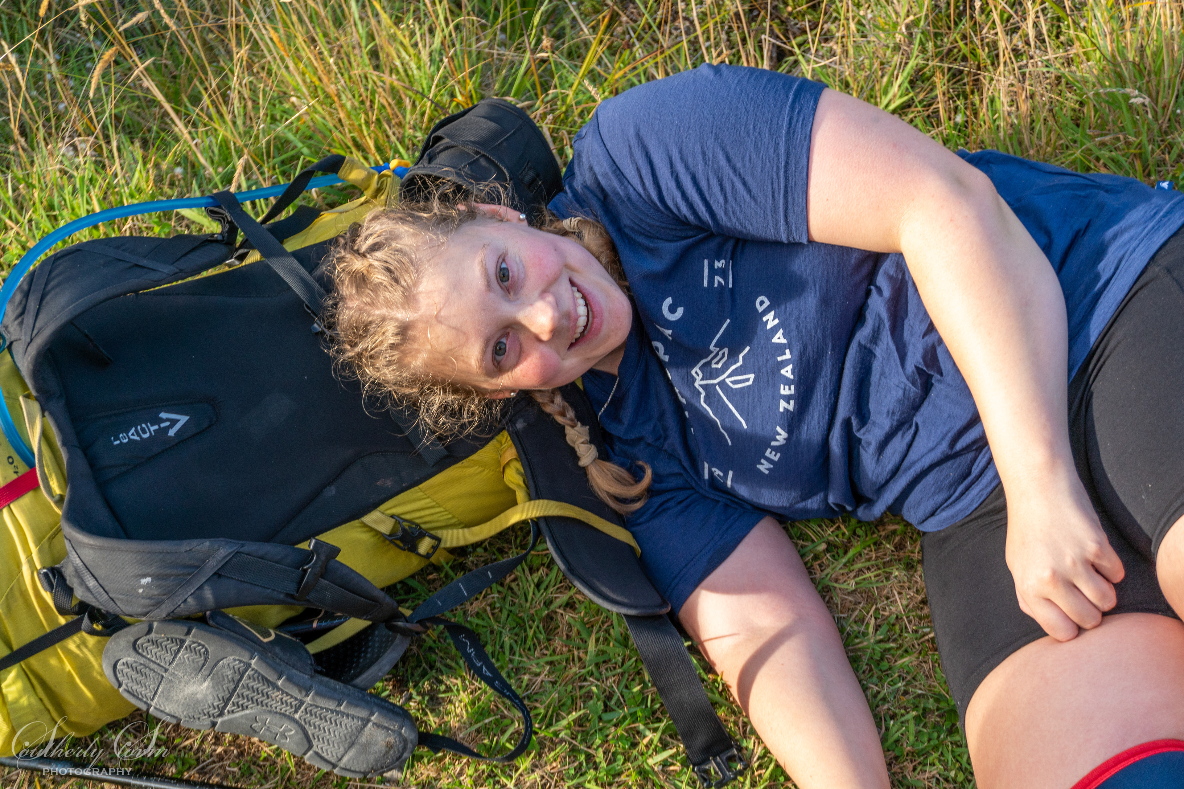 Charlotte lying on her pack in the middle of the track