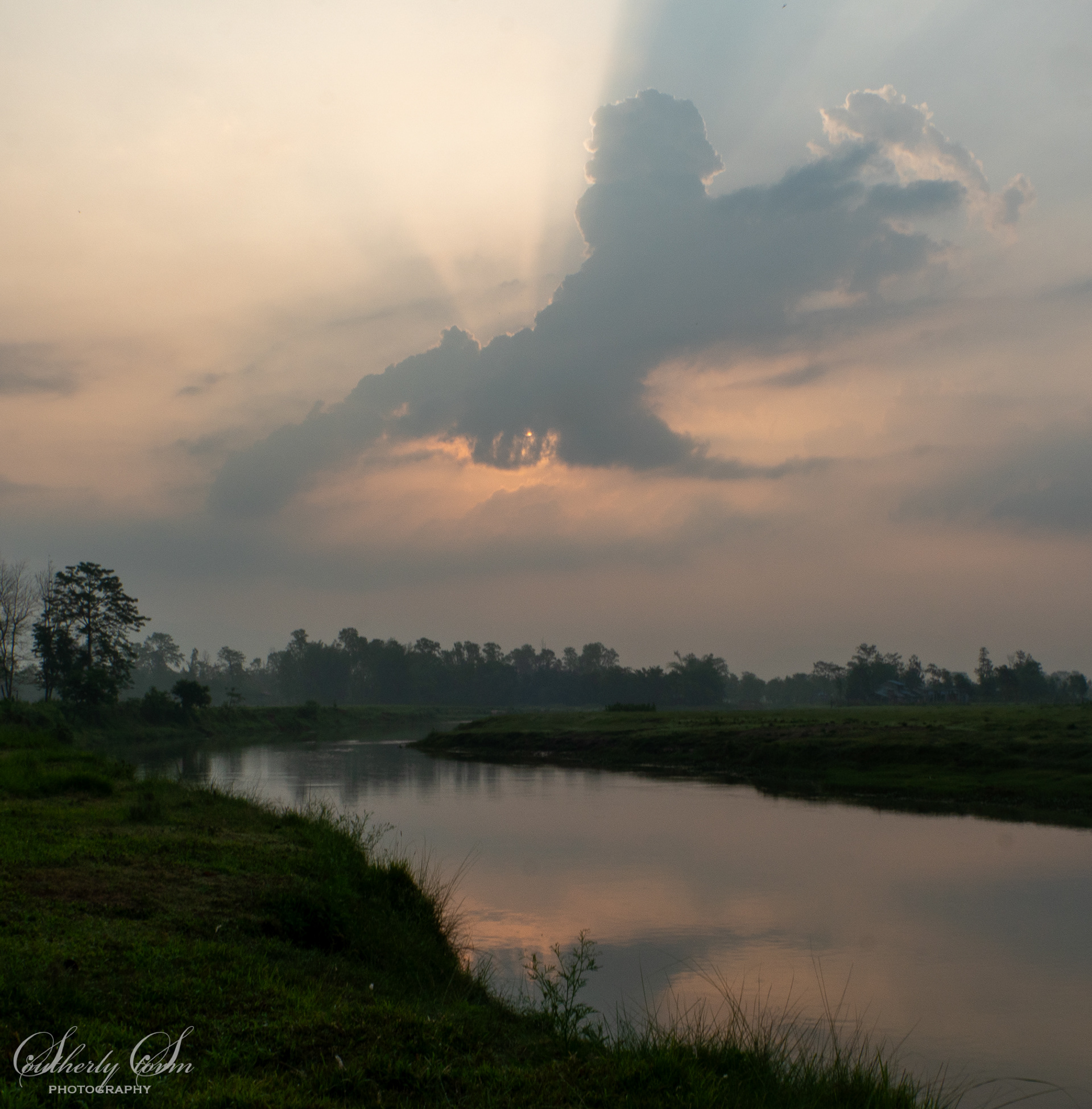 Sunrise behind clouds over the river