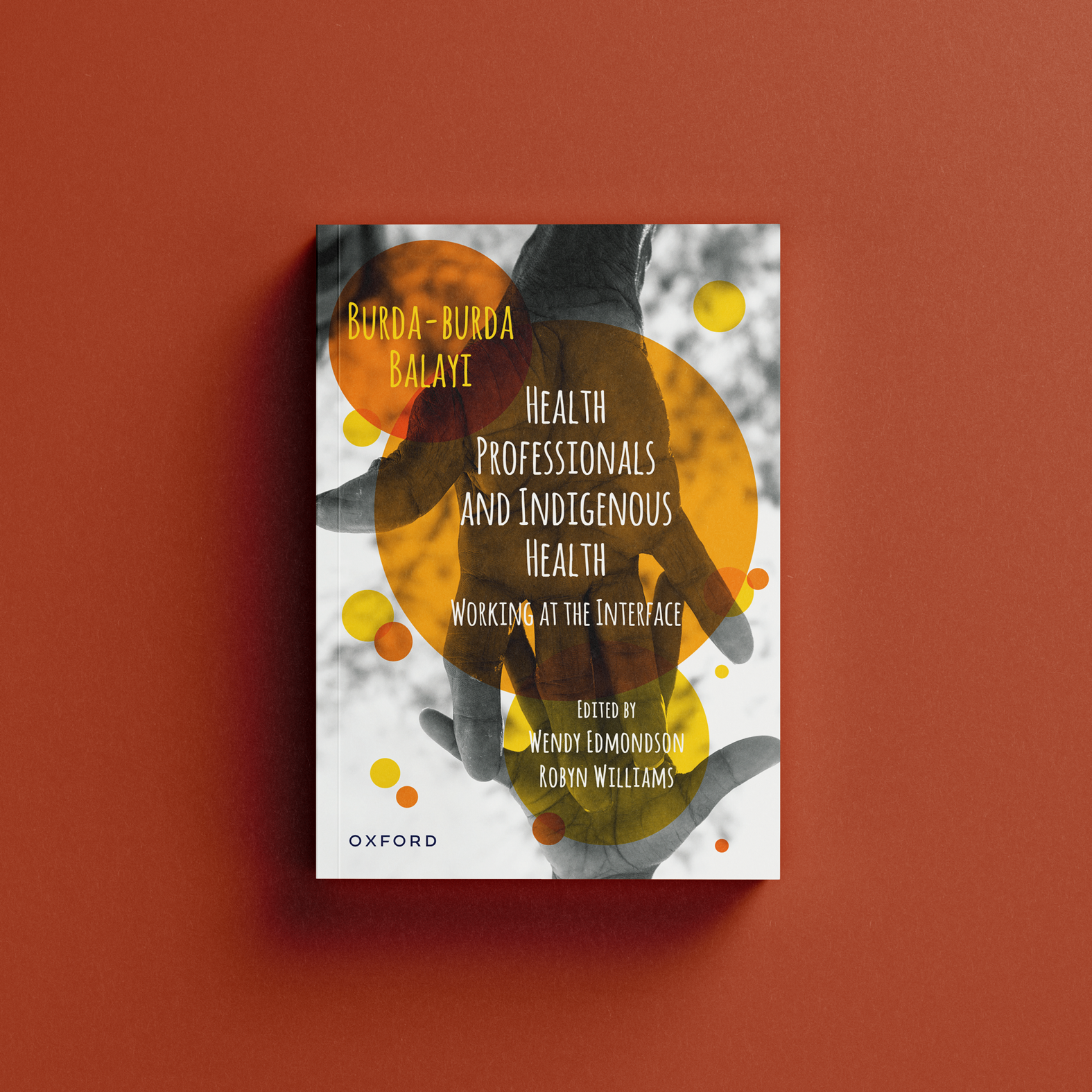 Book cover image of two hands - one belonging to a female Aboriginal elder and the other a child. The image is in black and white with orange and yellow circles on top.