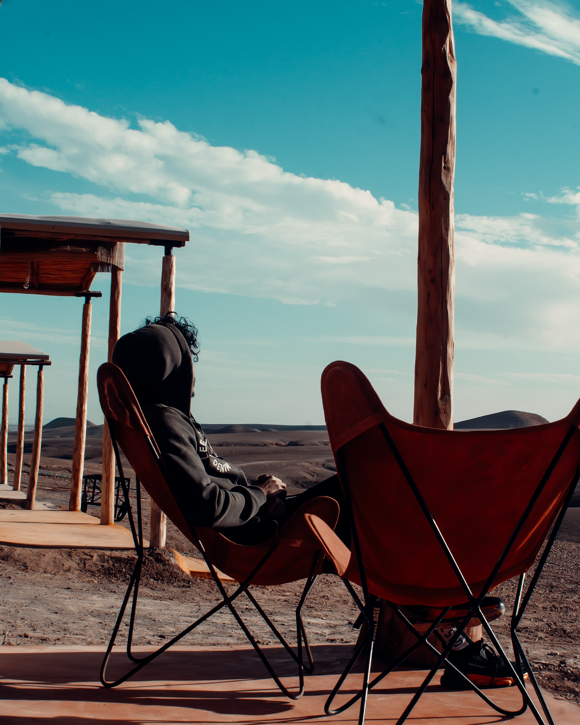 Temlyder — hotel terrace photography, rooftop seating with leather butterfly chairs against bright blue sky, hospitality brand content