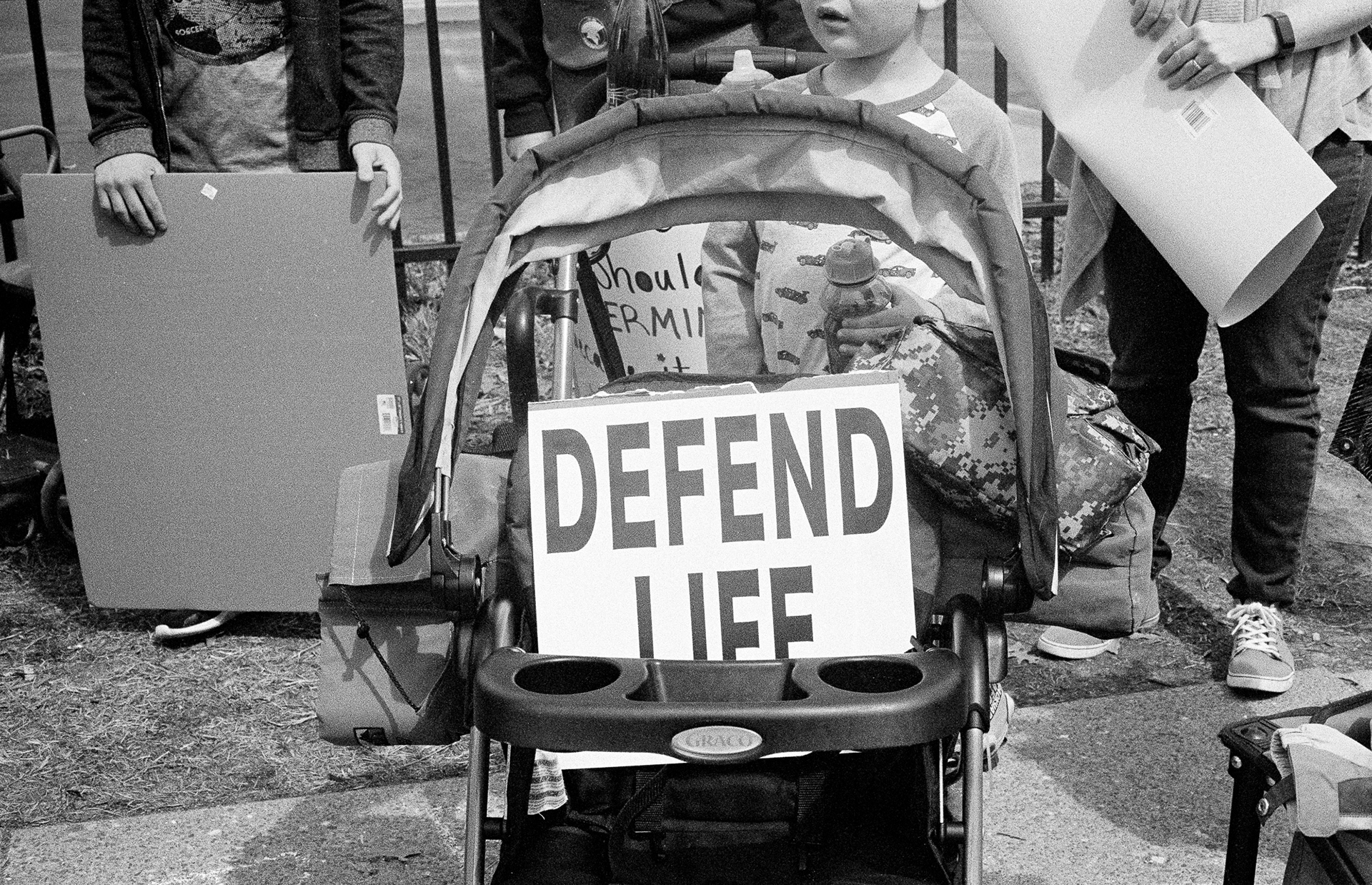 A "DEFEND LIFE" sign in a stroller, in front of a group of indistinguishable children