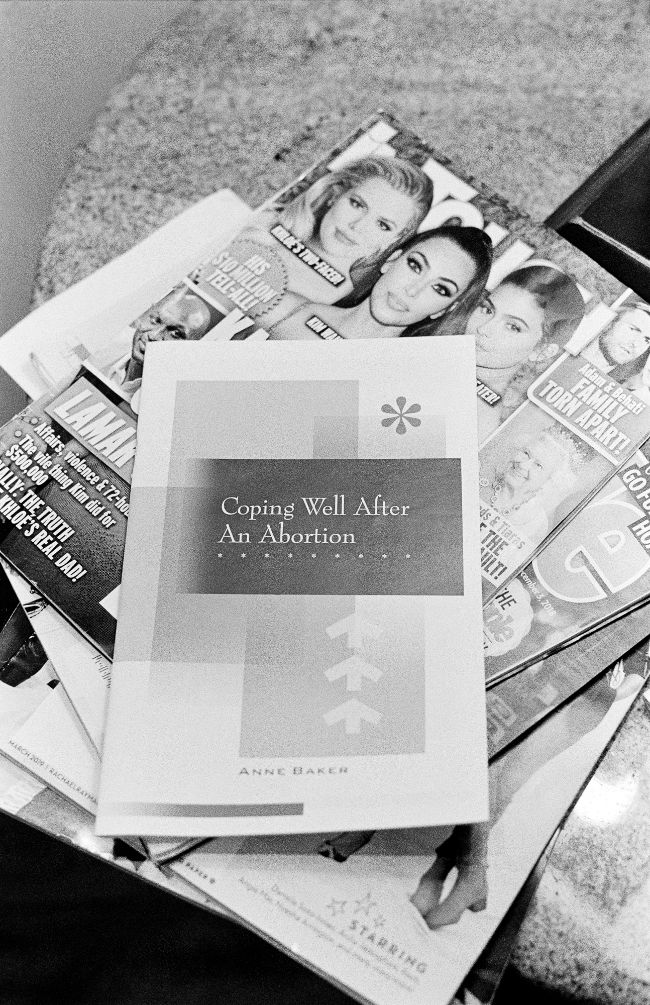 A "Coping Well After An Abortion" pamphlet atop a stack of gossip magazines