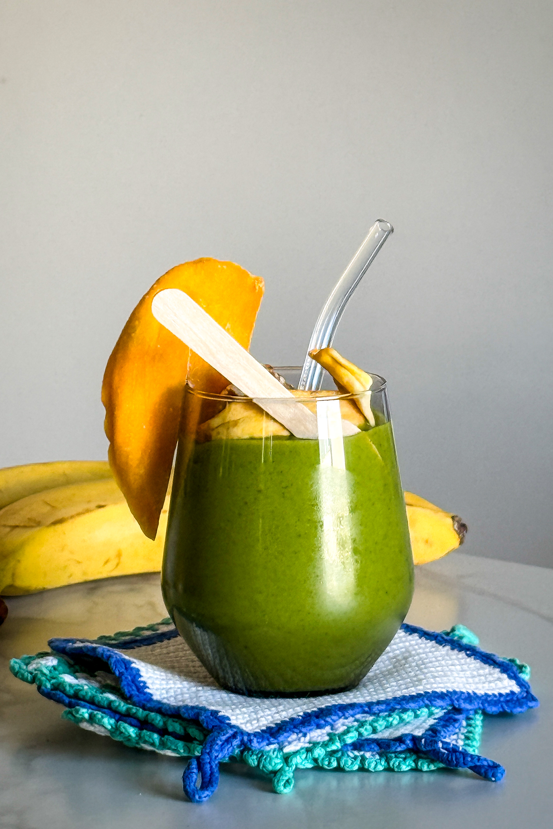 Green smoothie with slice of mango and some ectra nuts and dried fruit on top