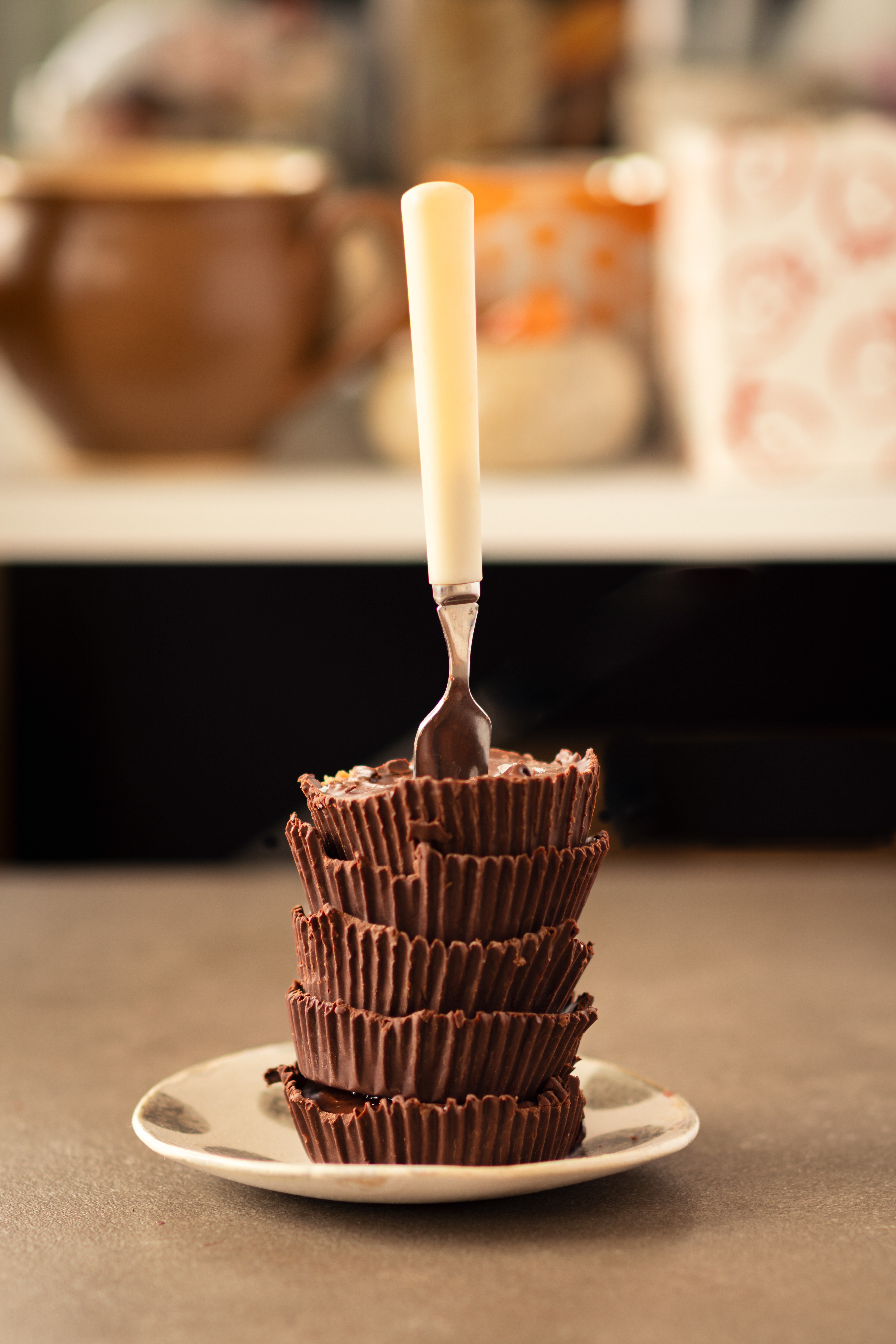 Close-up of stacked chocolate seed butter cups with a fork pressed into the top, highlighting the ridged chocolate edges and soft filling inside