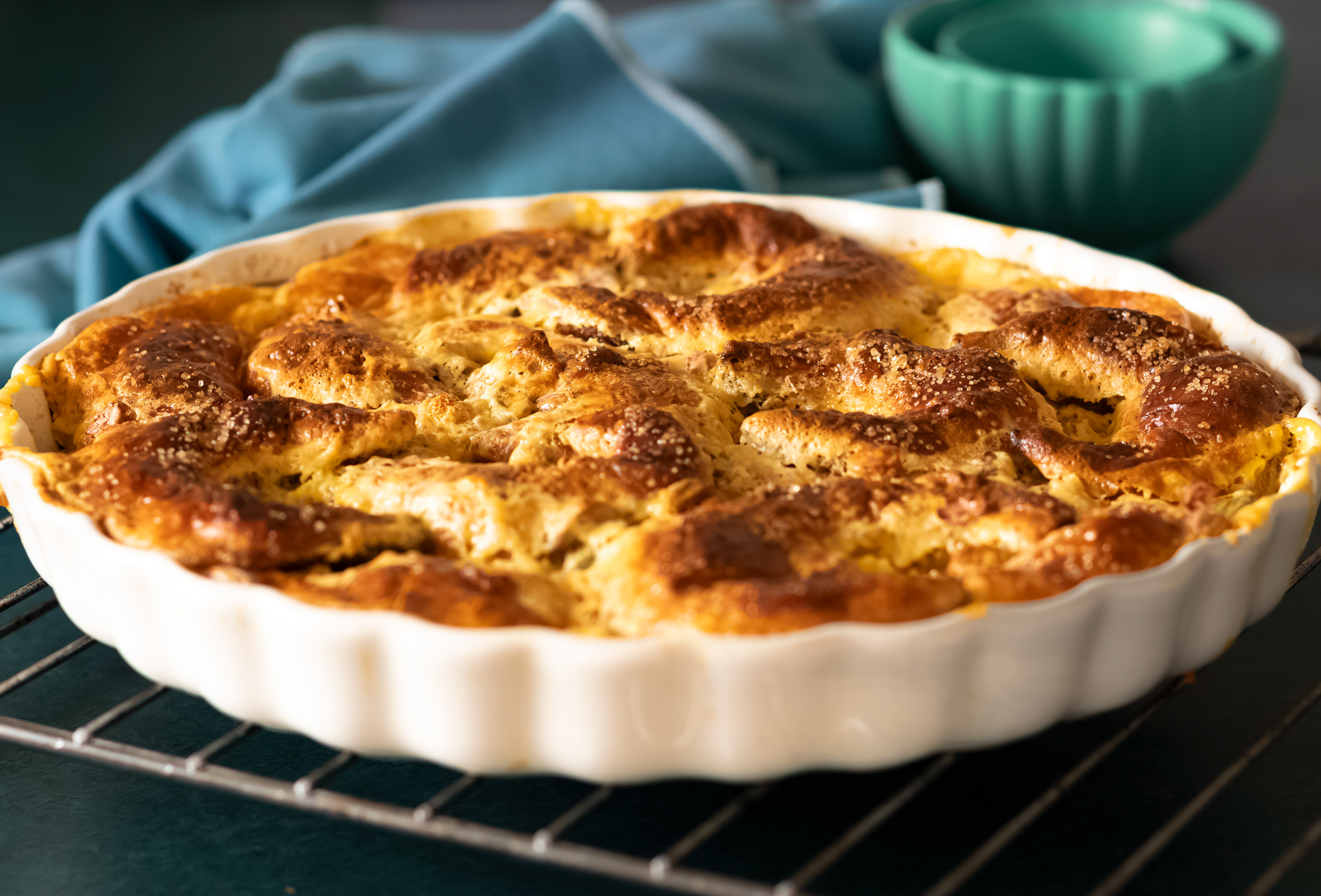 Yellow-brown bread pudding in a white oven dish, on dark green background