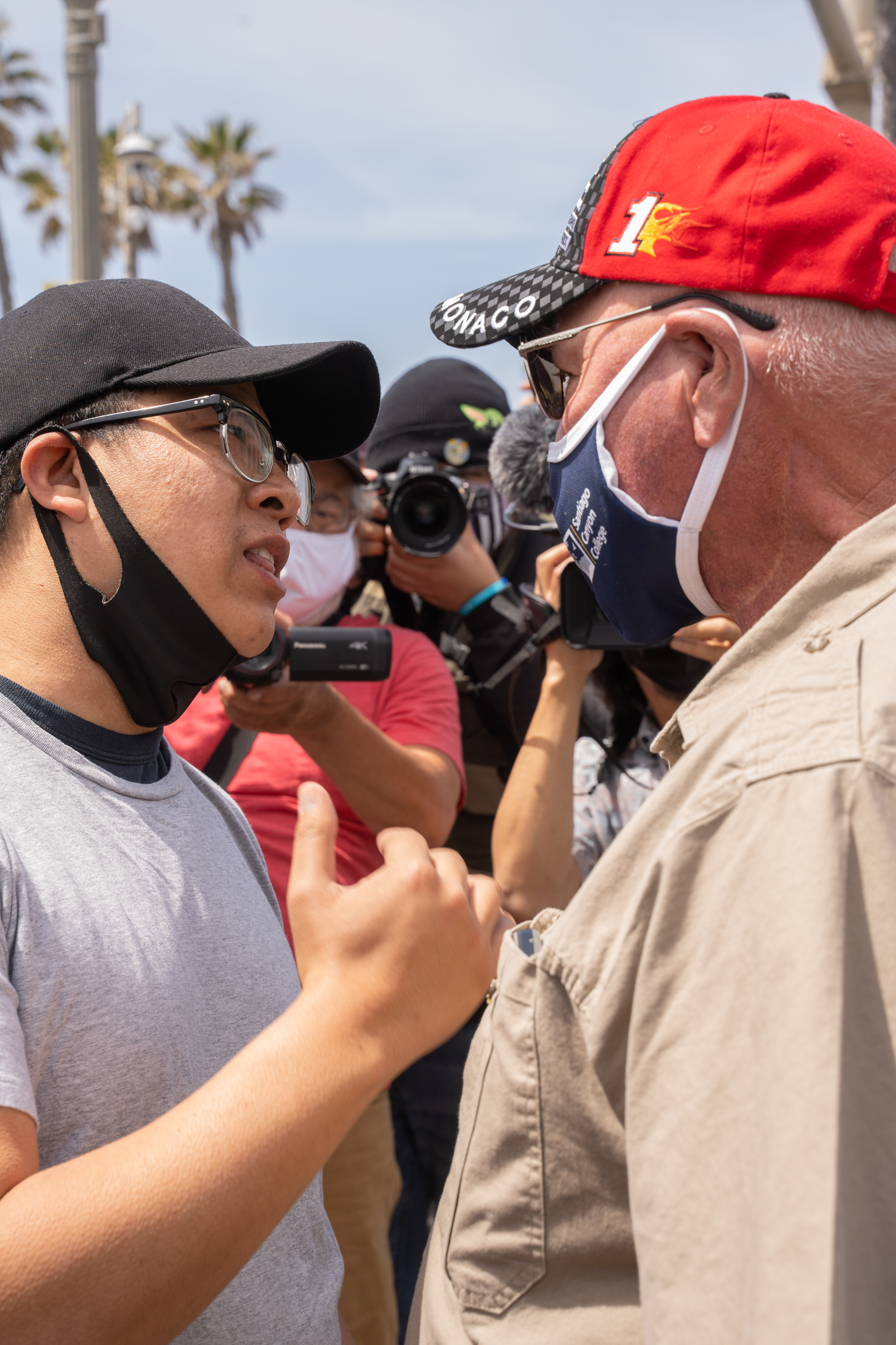 A young asian protester, left, explains the purpose of the rally to a local, right. The man in the red hat began chanting "dog lives matter" claiming that protesters should be more concerned about the deaths of local pets. Sunday, April 11, 2021. (Photo by Solomon O. Smith/ The Valley Star)