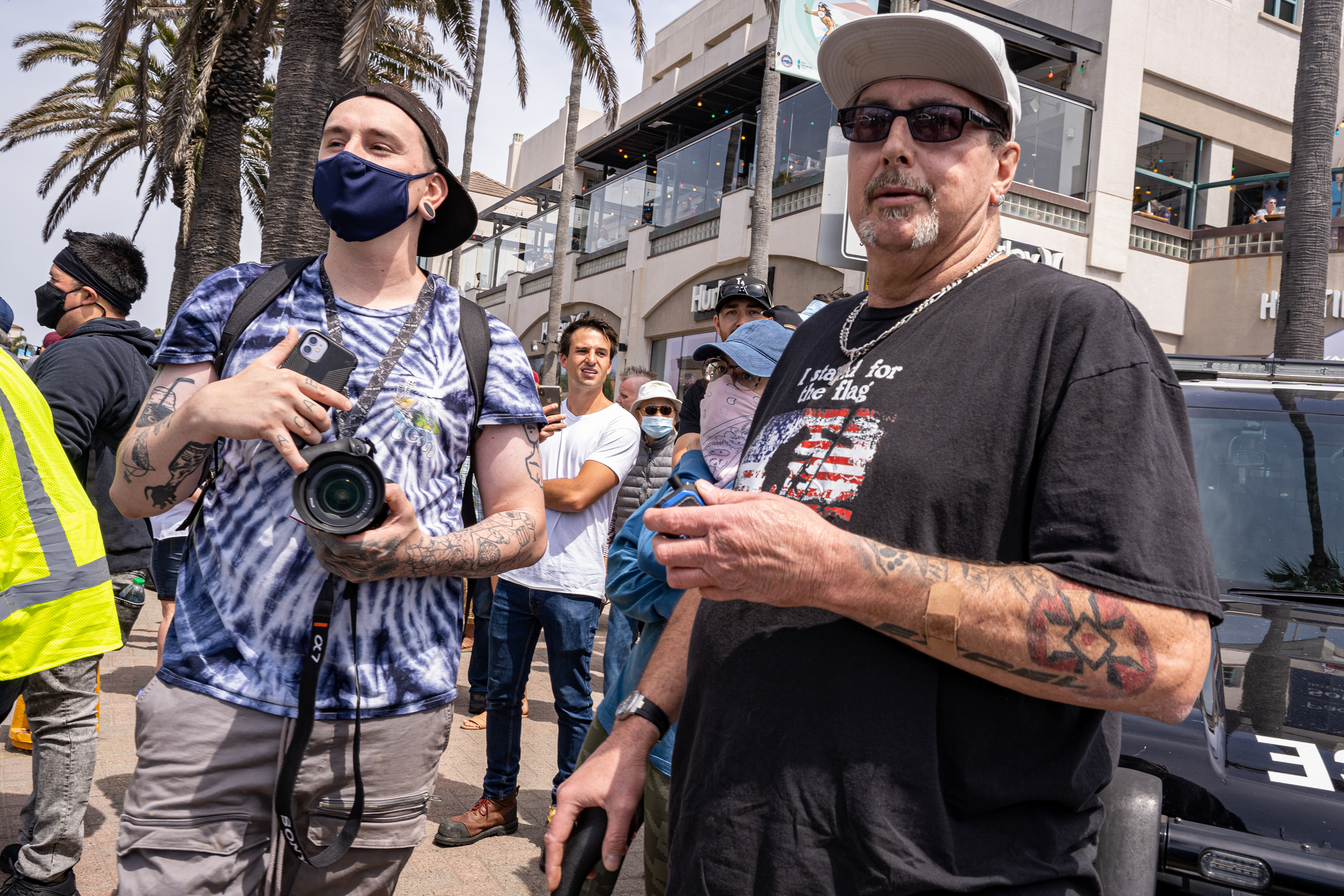Two white supremecists talk about the protest while flashing thier tattoos. The young man on the right flashes the skin head tattoo "ACAB" meaning "all cops are bastards" while the older man on the right, William Quigg,  flashes the traditional cross of the KKK. Both men denied any affiliation when asked about the tattoos, but Quigg is rumored to be a high ranking official in the California KKK.. (Photo by Solomon O. Smith)