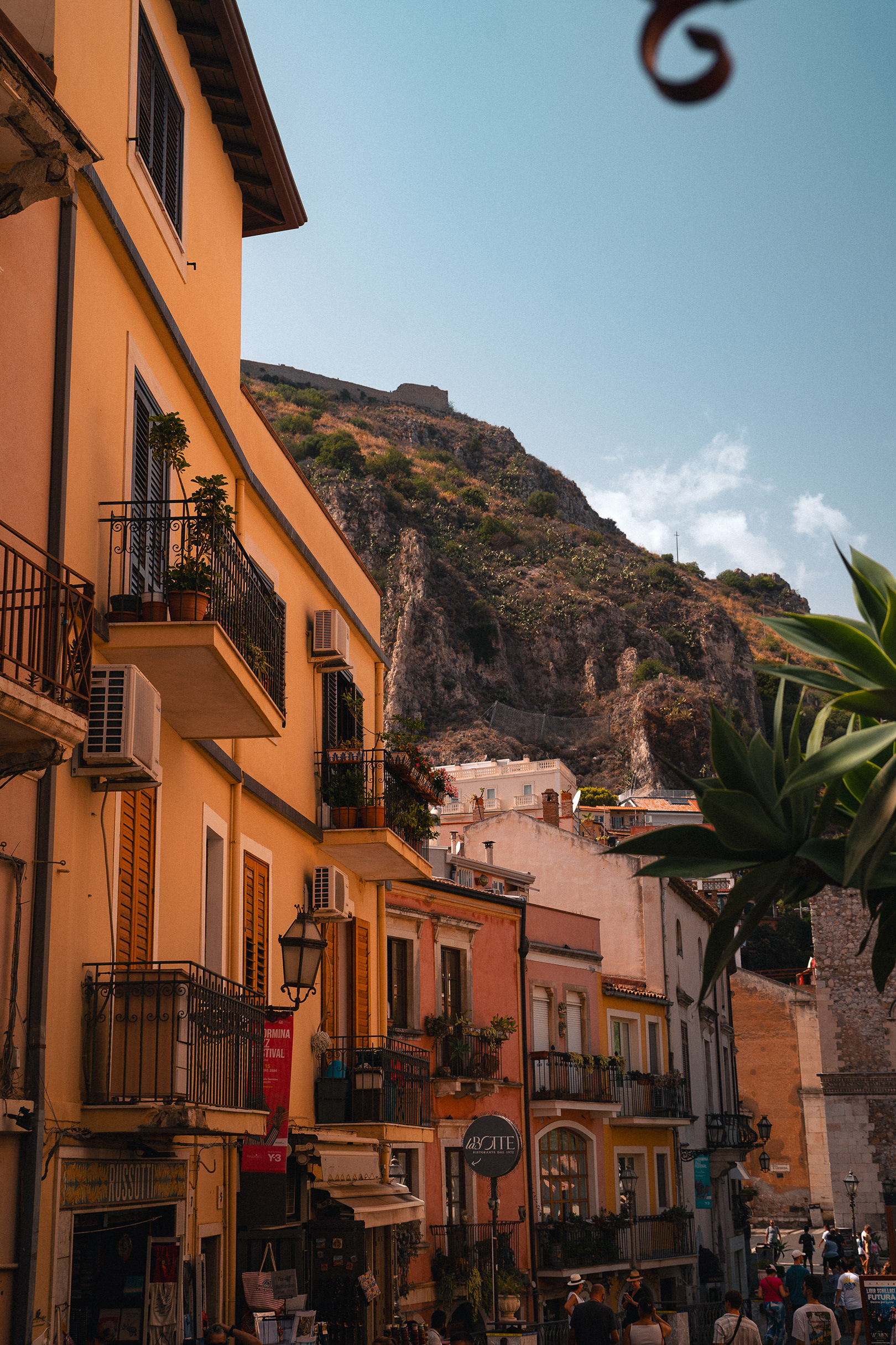 Rue typique de Taormine avec balcons fleuris et architecture sicilienne, vue par Sabri Kaced.