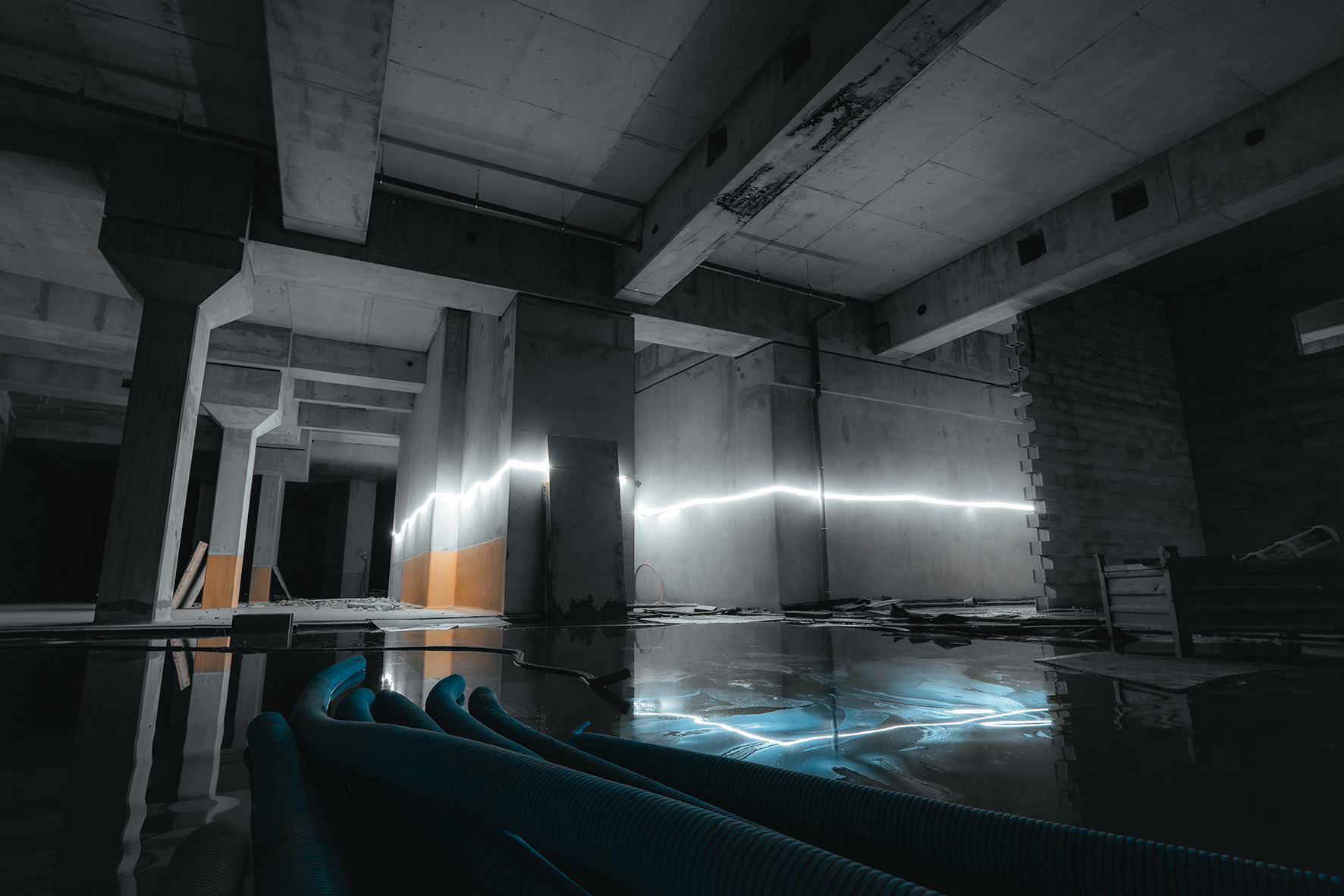 Photographie artistique d'un sous-sol de chantier avec ruban lumineux LED et reflets bleutés, projet Austerlitz à Paris par le photographe Sabri Kaced.