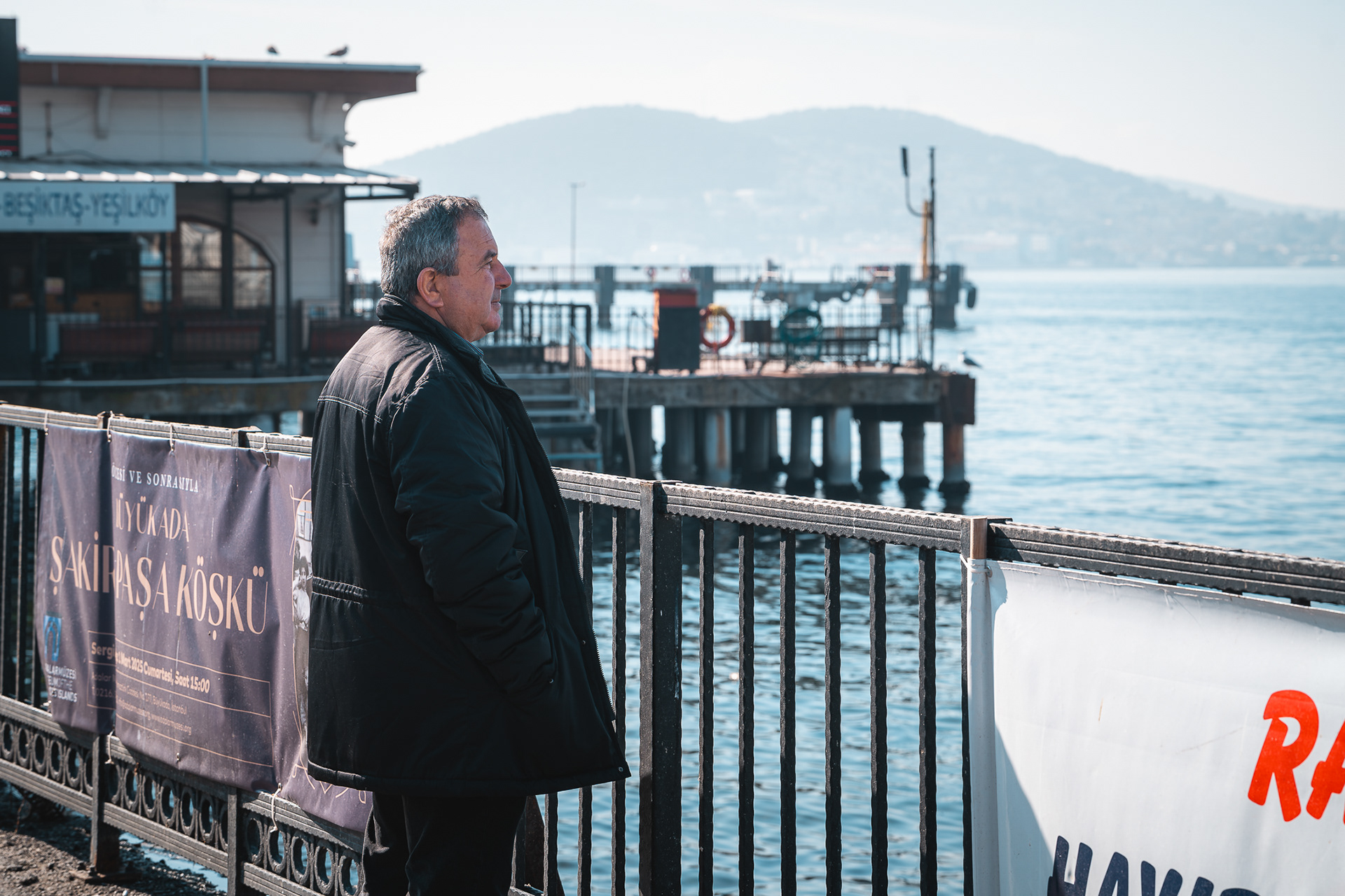 Un homme observe la mer depuis un quai à Istanbul, capturant l'atmosphère paisible de la ville par Sabri Kaced.