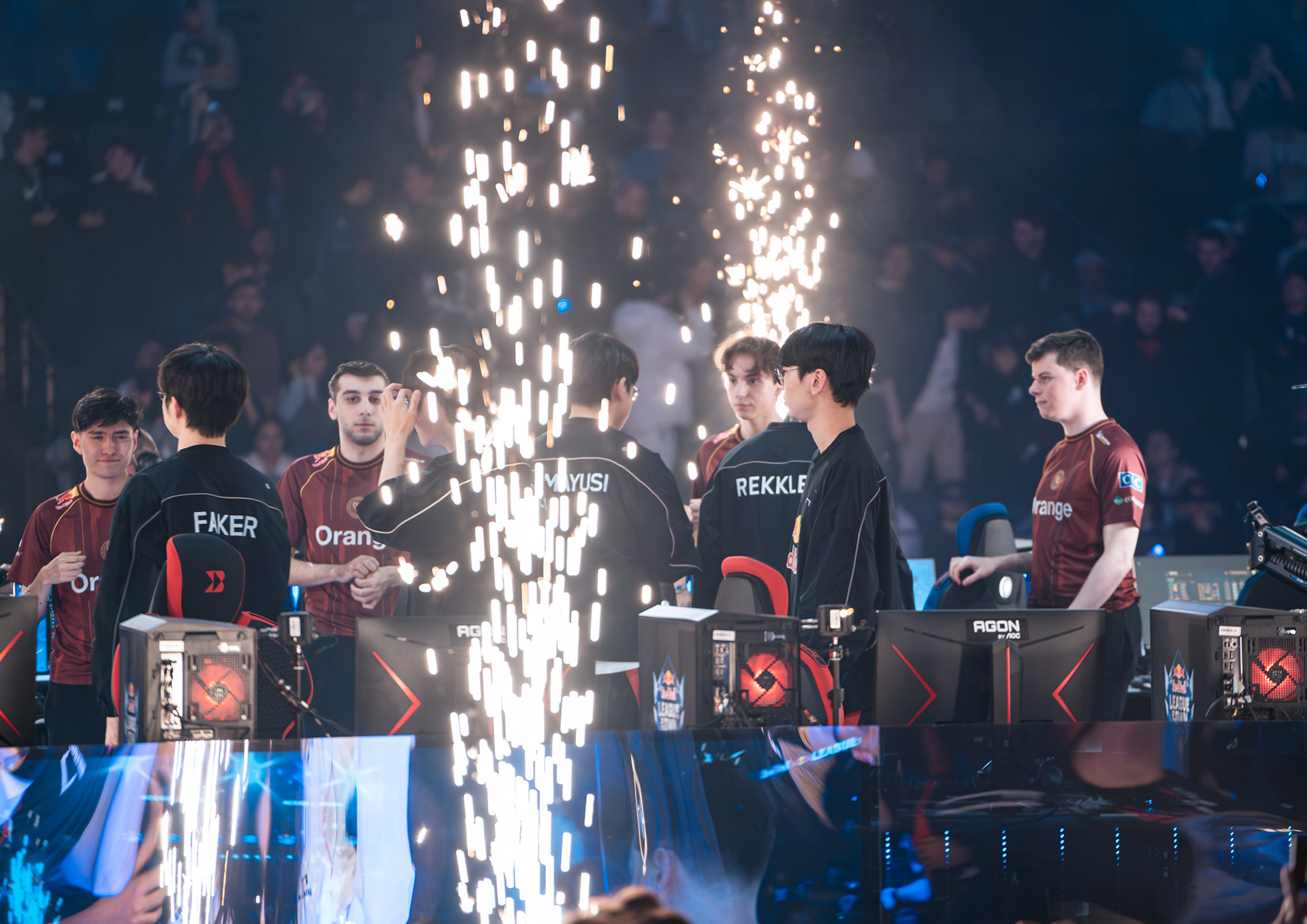 Joueurs des équipes T1 et Karmine Corp sur scène entourés d'effets pyrotechniques et d'étincelles lors de la présentation du match.