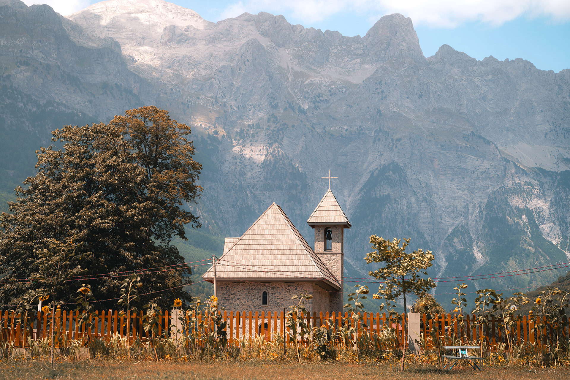 Paysage emblématique de l'église de Theth se dressant devant les impressionnantes montagnes des Alpes albanaises sous un ciel bleu. Photo : Sabri Kaced.
