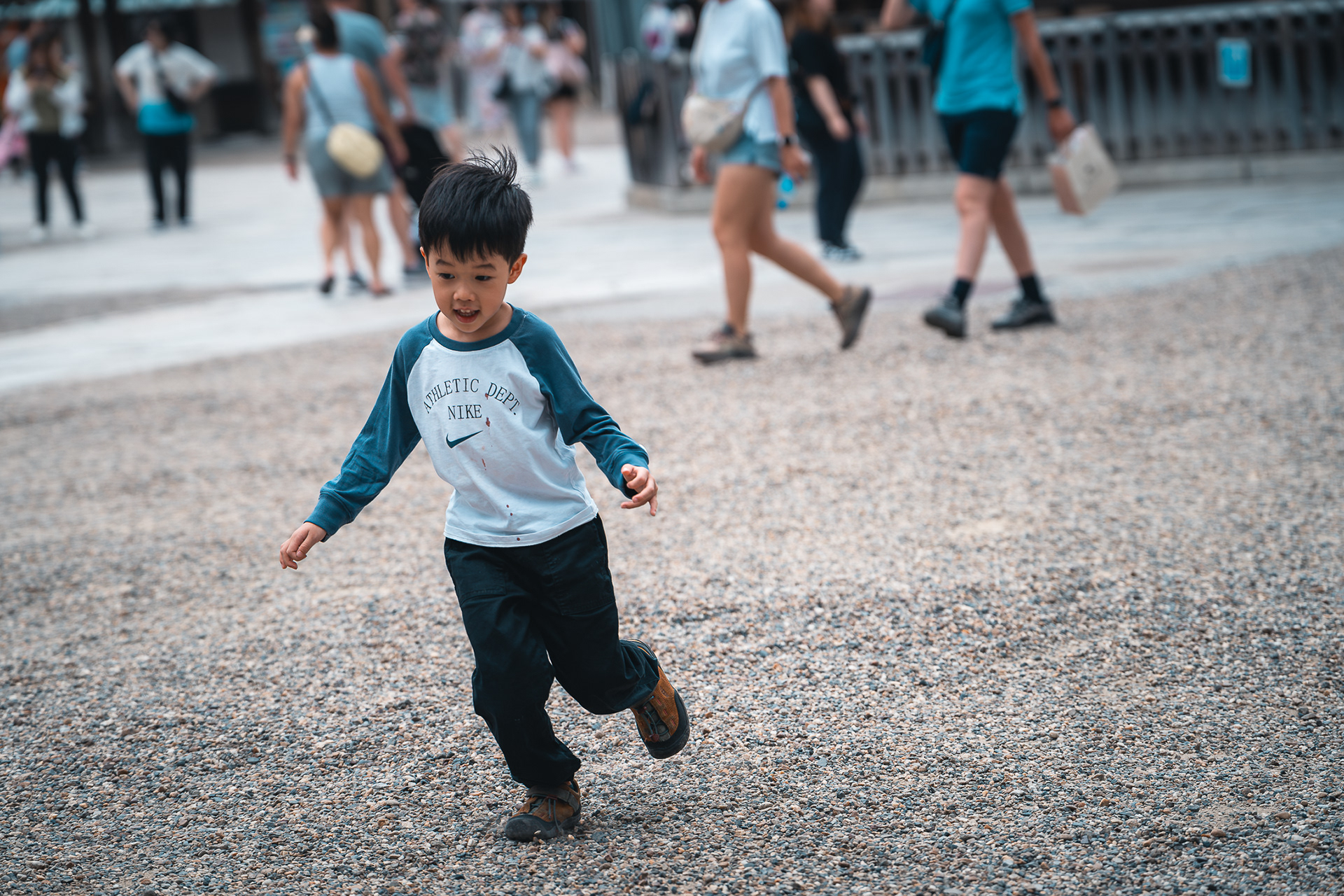 Photoreportage de Sabri Kaced montrant un jeune garçon en mouvement qui court sur un sol de graviers dans un lieu public.
