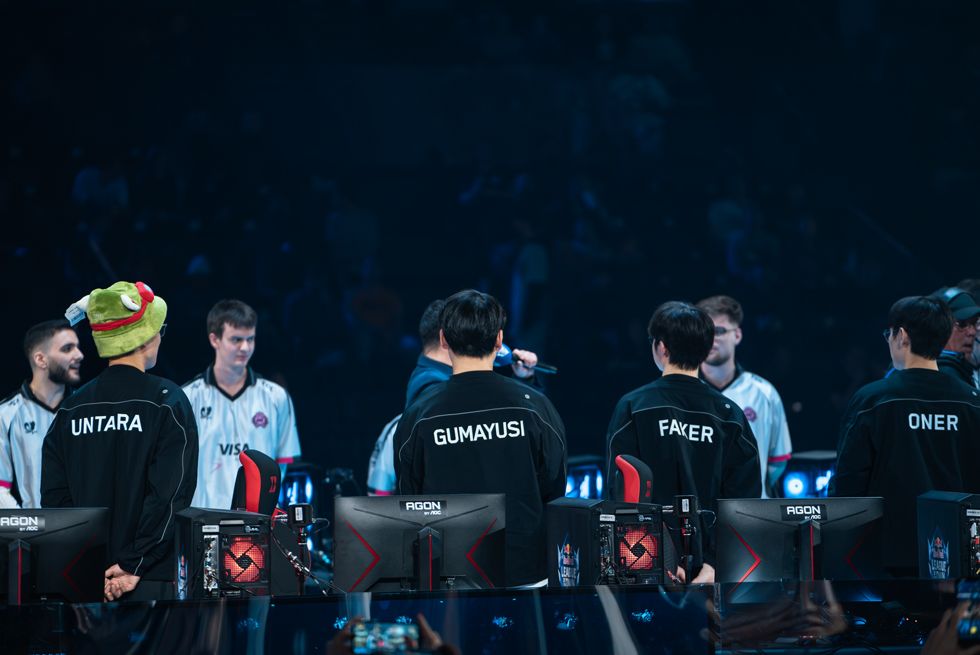 Les joueurs de l'équipe T1 (Untara, Gumayusi, Faker, Oner) de dos devant leurs postes de jeu AGON lors du tournoi Red Bull League of Its Own.