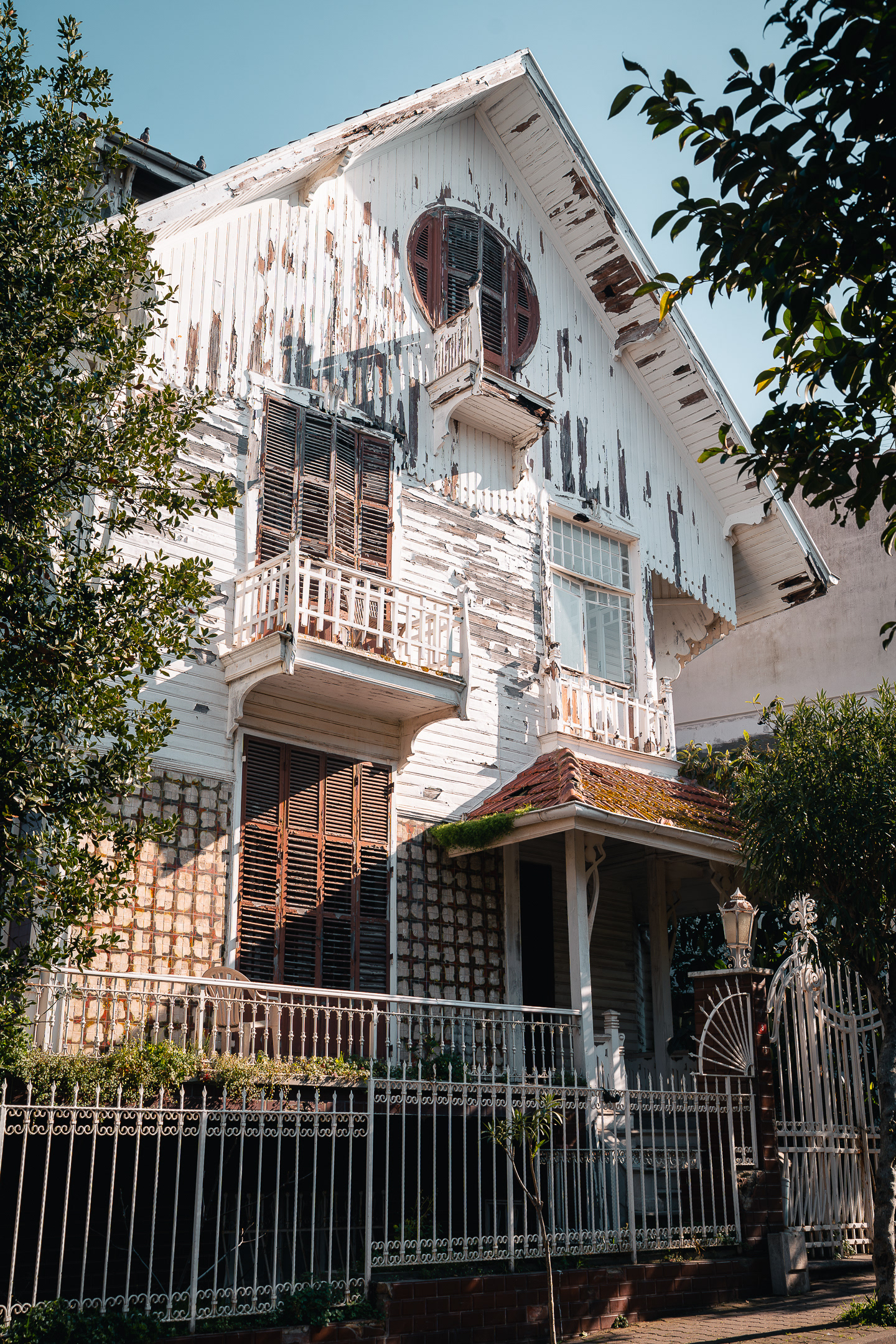 Architecture ottomane d'une villa blanche aux peintures écaillées avec des balcons en bois, photographiée par Sabri Kaced.