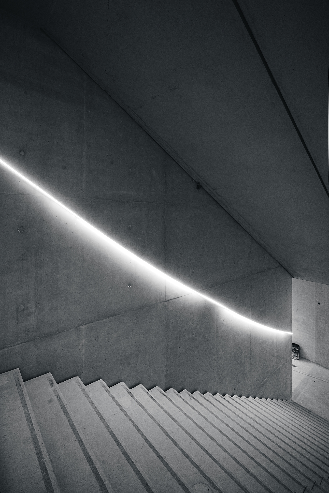 Photographie artistique en noir et blanc d'un escalier de chantier à la Gare d'Austerlitz par Sabri Kaced, montrant un jeu de lumière linéaire sur du béton brut.