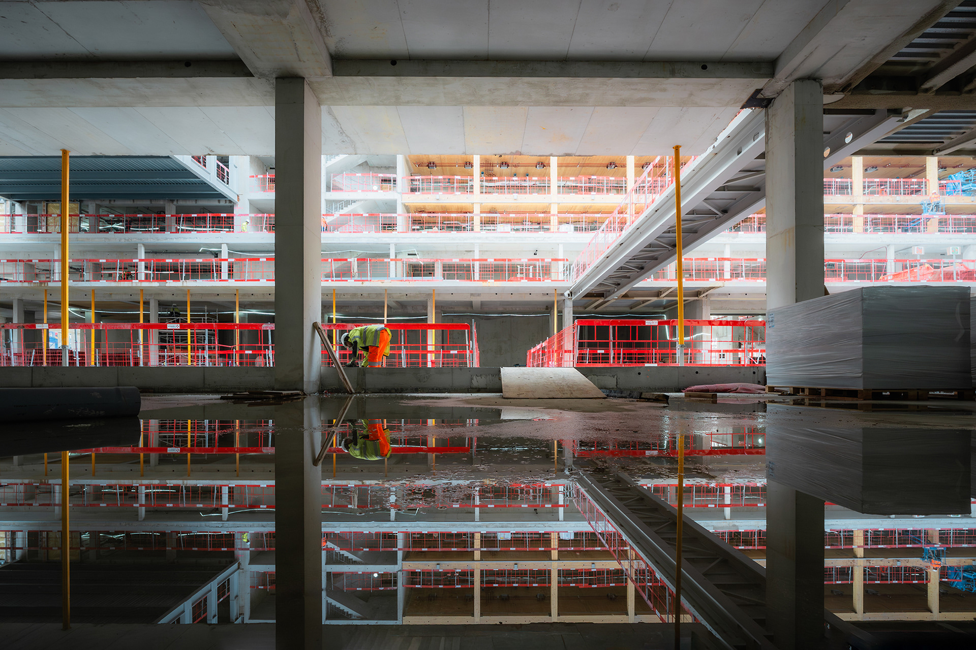 Ouvrier travaillant sur le chantier de la Gare d'Austerlitz avec reflet symétrique parfait dans l'eau, prise de vue professionnelle par Sabri Kaced.