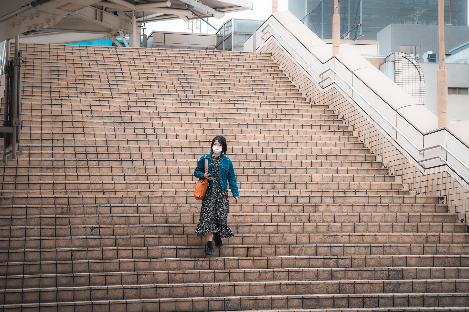 Composition architecturale de Sabri Kaced montrant une femme descendant un immense escalier extérieur moderne dans un quartier urbain.