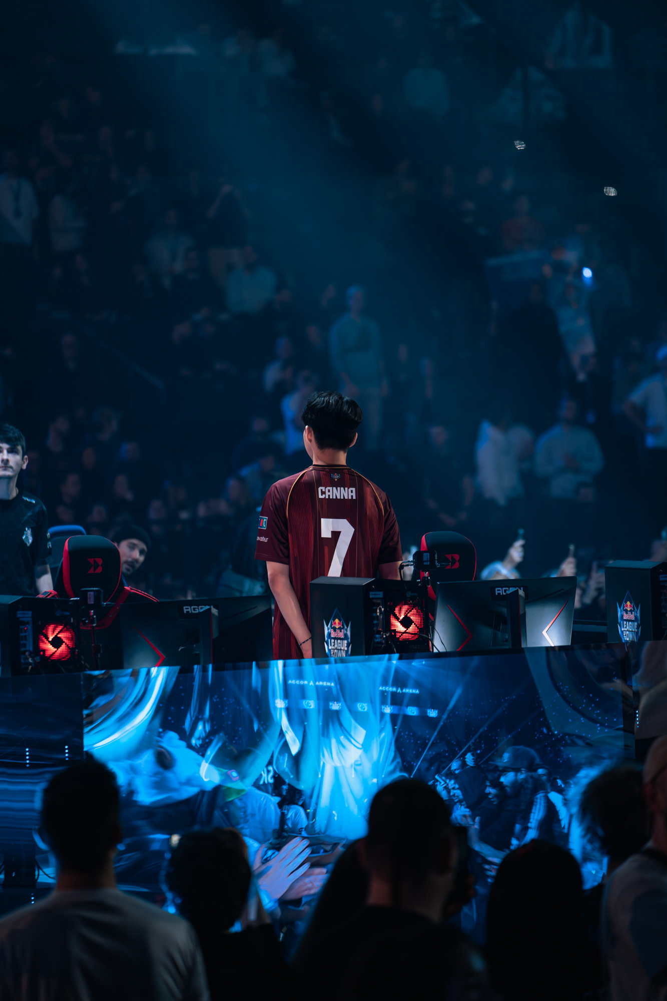 Le joueur Canna de la Karmine Corp, de dos avec son maillot floqué du numéro 7, observant la salle immense depuis la scène principale.