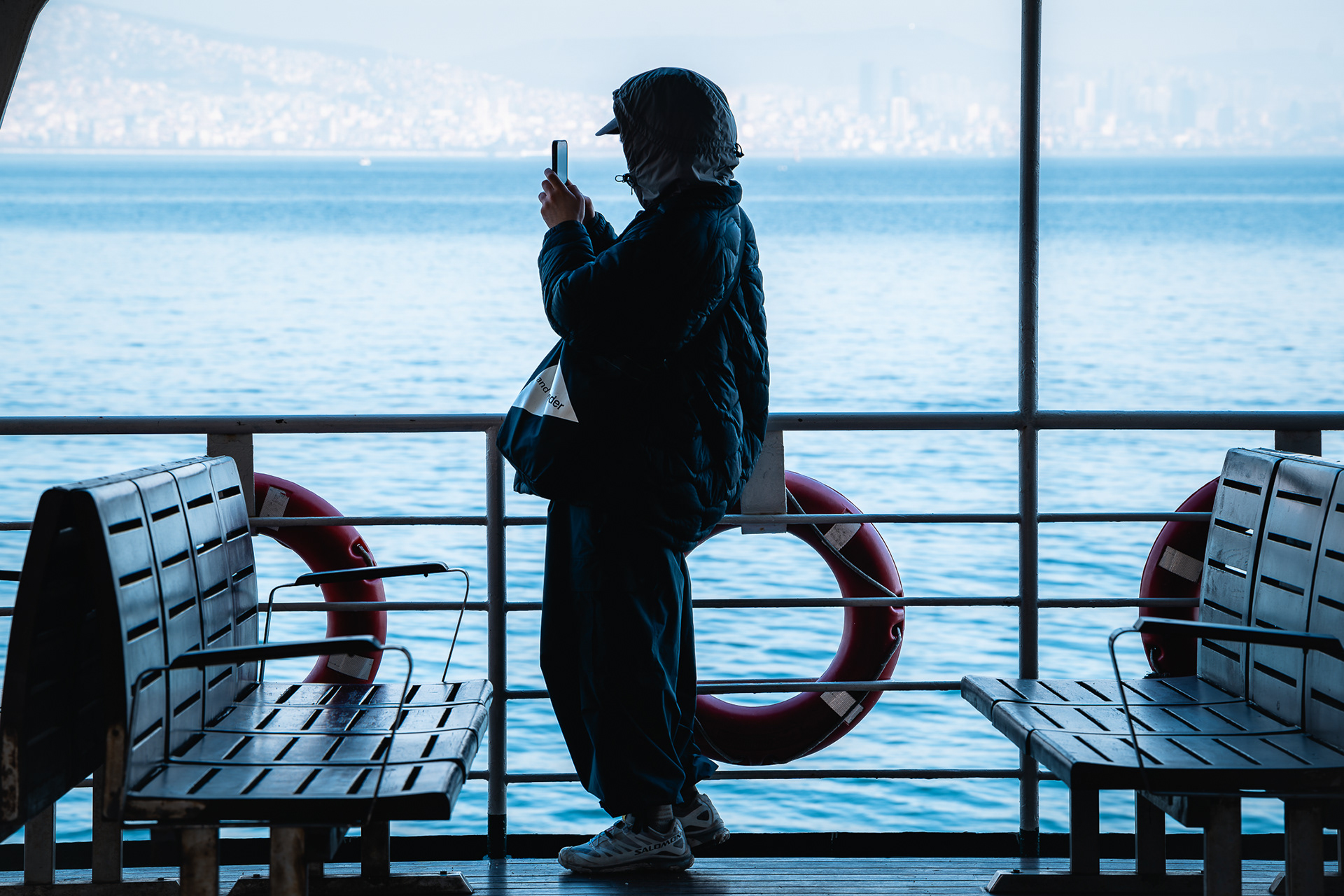 Silhouette d'un voyageur contemplant l'horizon depuis le pont d'un ferry, une photo documentaire de Sabri Kaced.