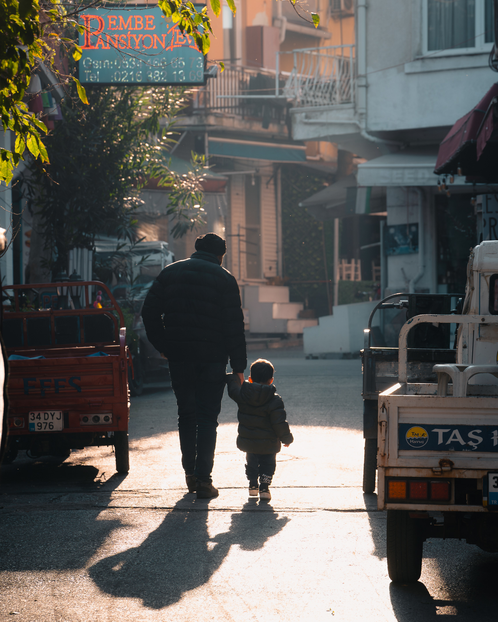 Portrait humaniste de Sabri Kaced montrant un père et son jeune enfant marchant main dans la main dans une ruelle ensoleillée.